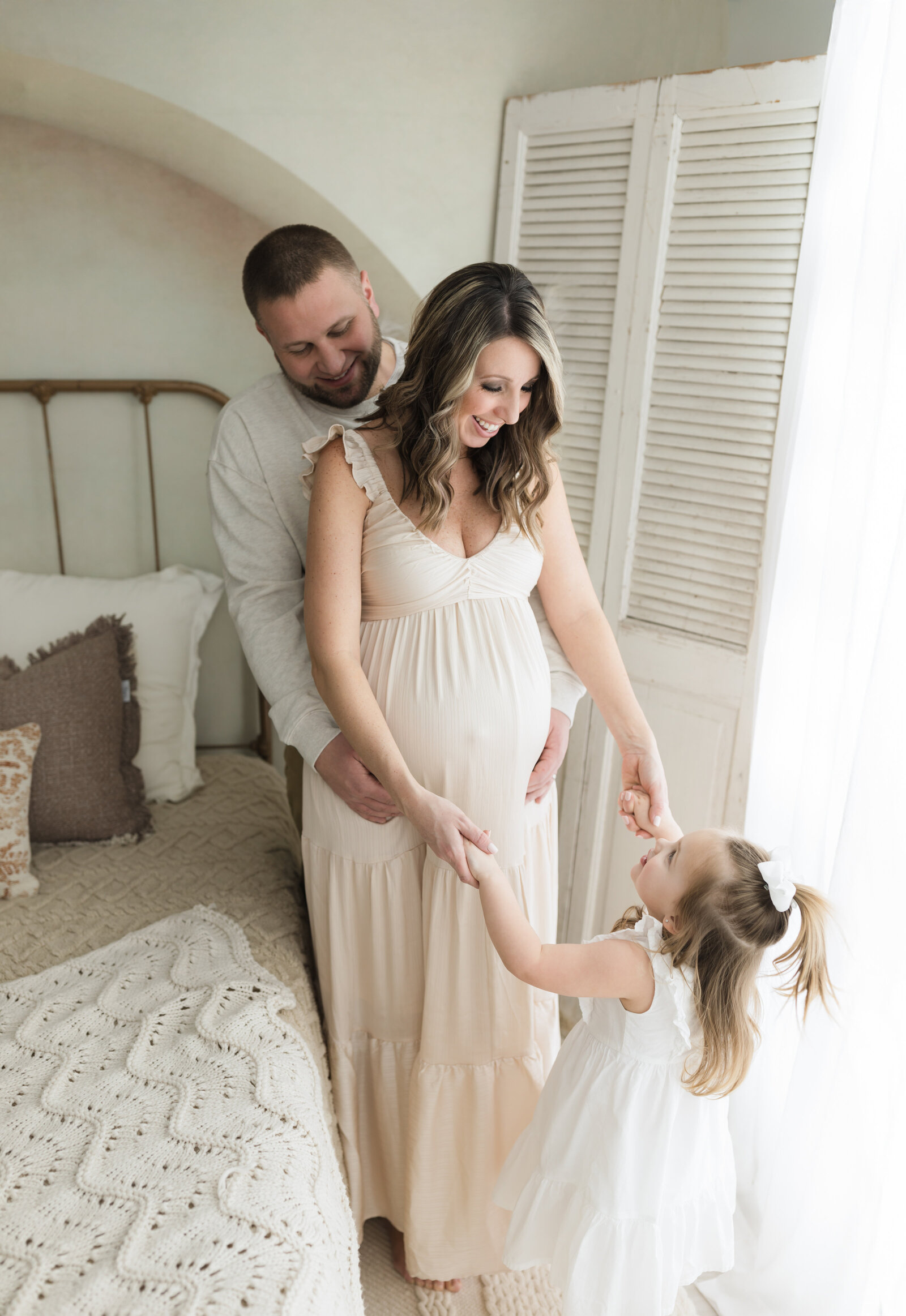 pregnant mother in cream maternity gown with daughter and husband for maternity photoshoot 