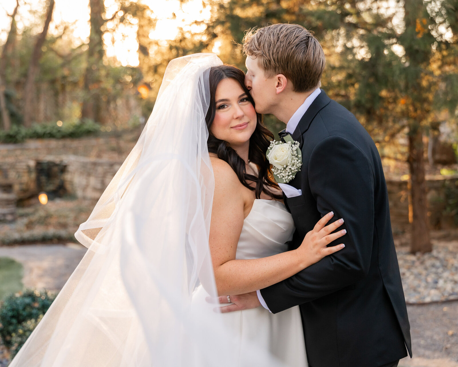 groom kissing his bride with veil
