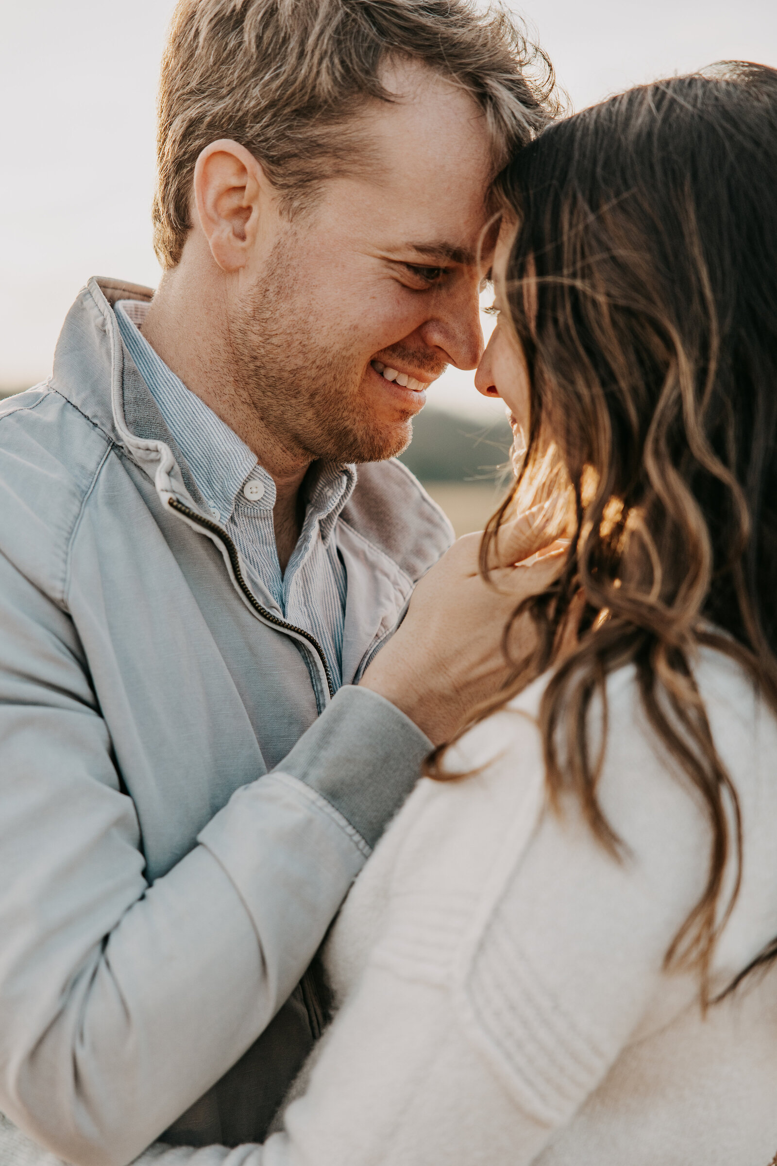 Kelly and Jordan in a sunlit field at Shelby Farms, Jordan gently holding Kelly’s face while smiling at her.