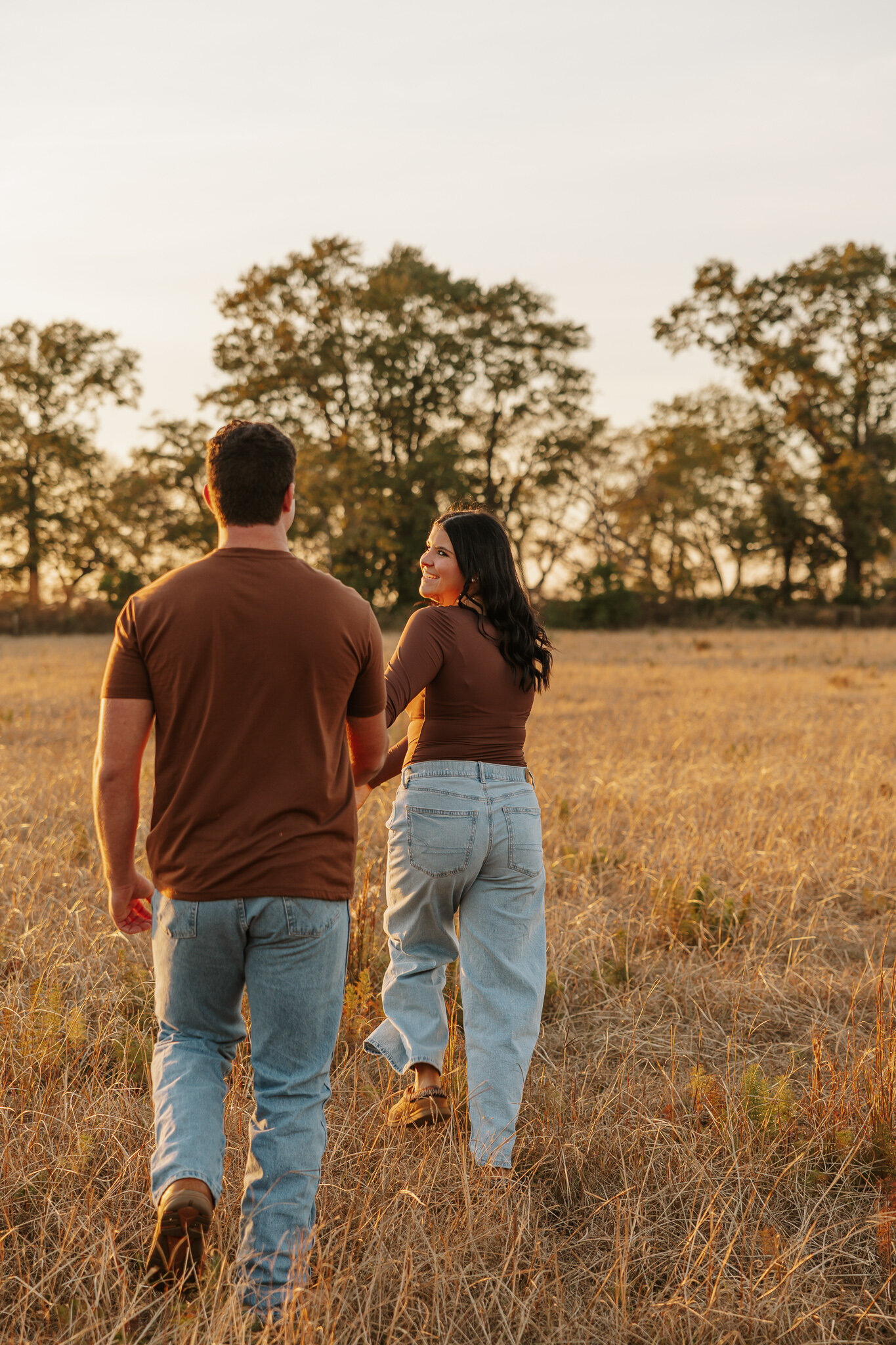 Couples session in a farm field in Aiken SC - couple running hand in hand through tall grass during golden hour.
