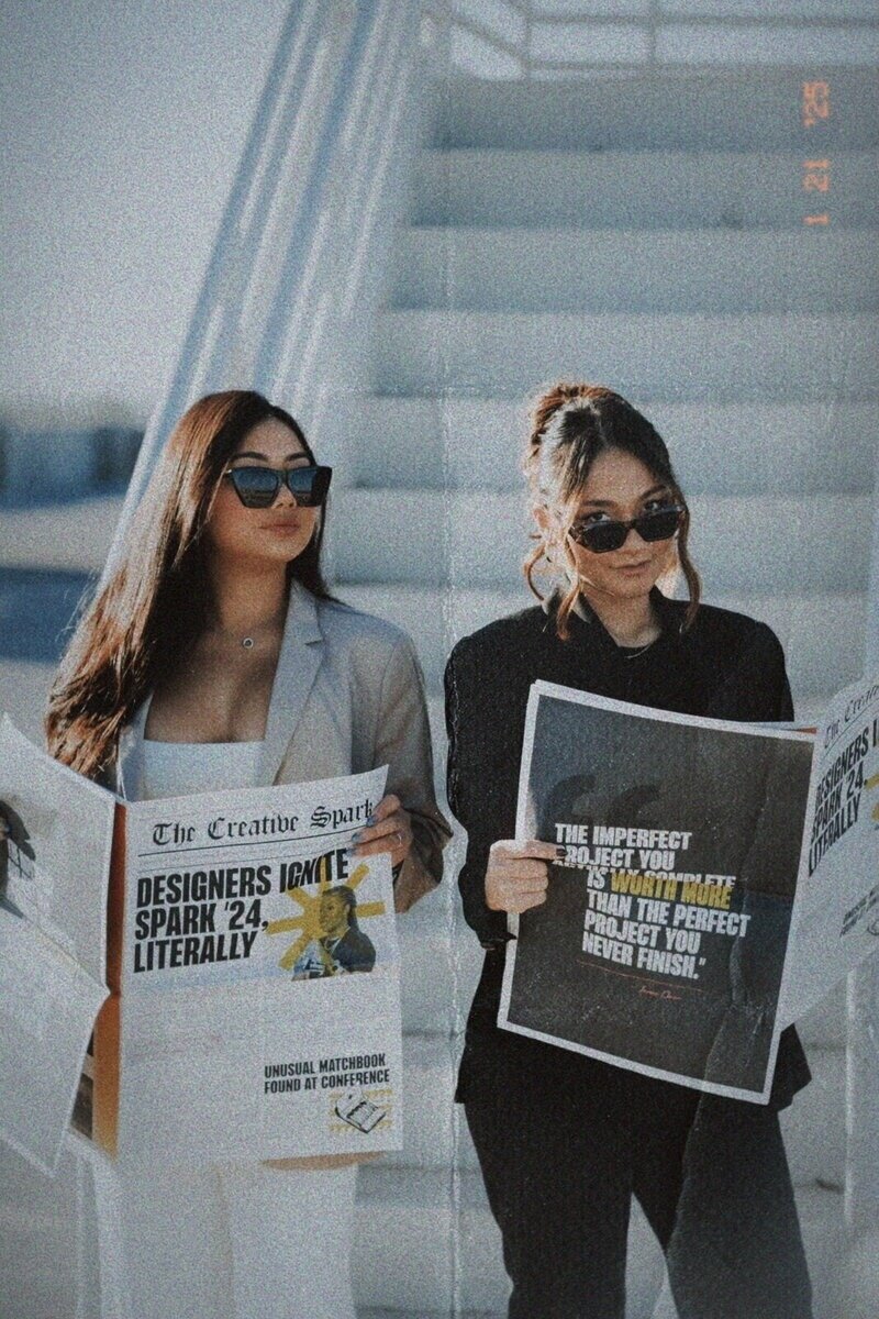 Two Showit web designers from Kemotion reviewing newspapers for creative inspiration.