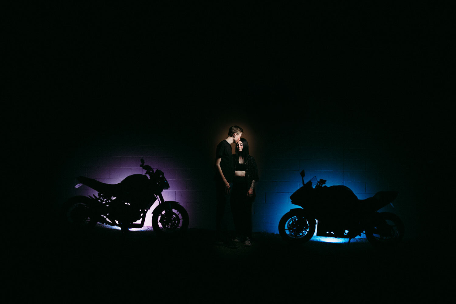 Night photo highlighting motorcycles in color and couple in middle