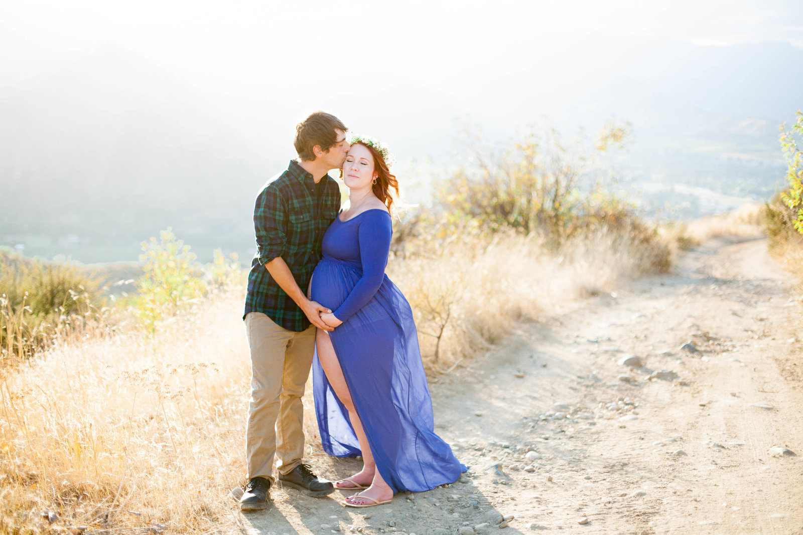 A woman wearing a blue dress kissing her husband.