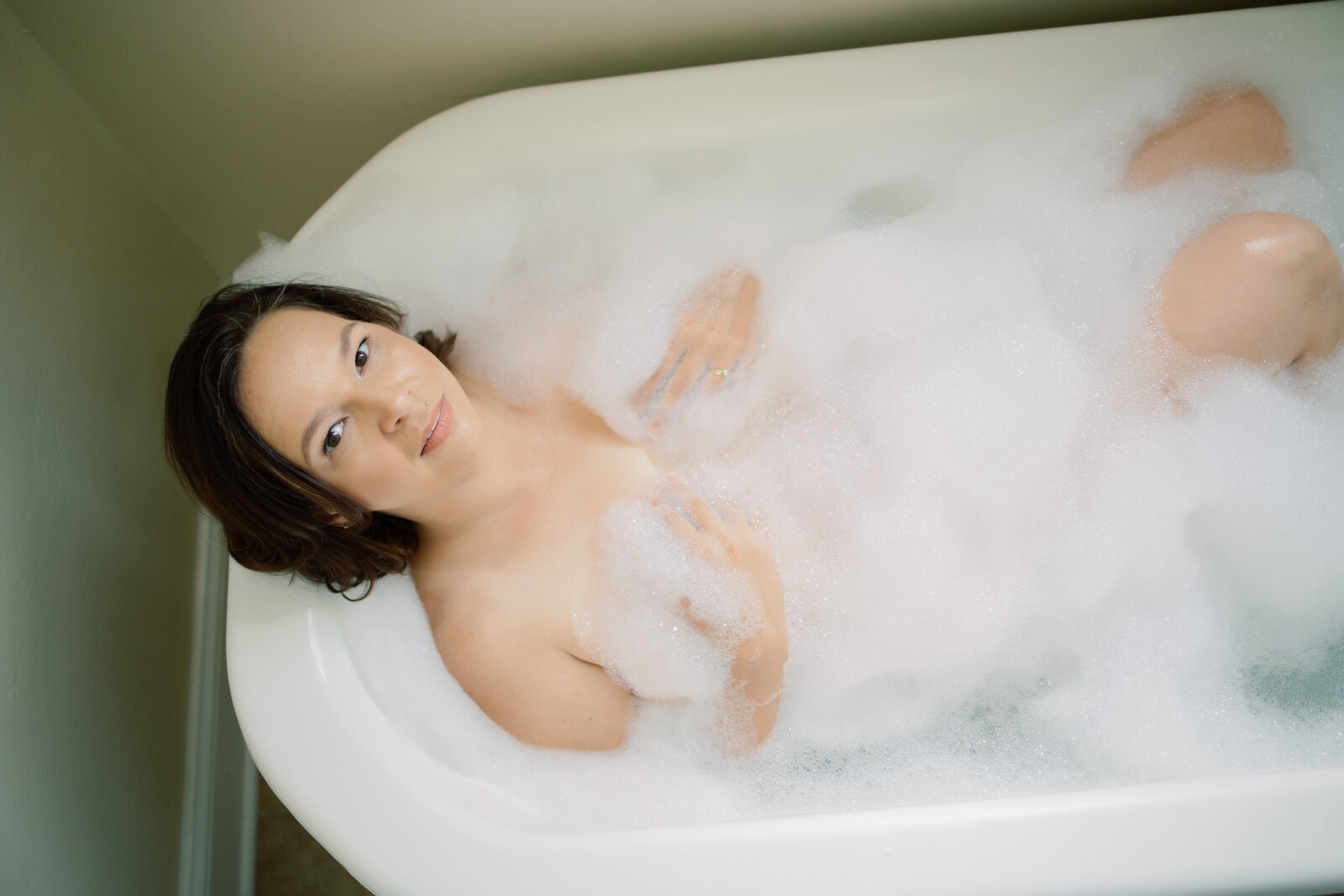 Woman lying in bathtub with bubbles