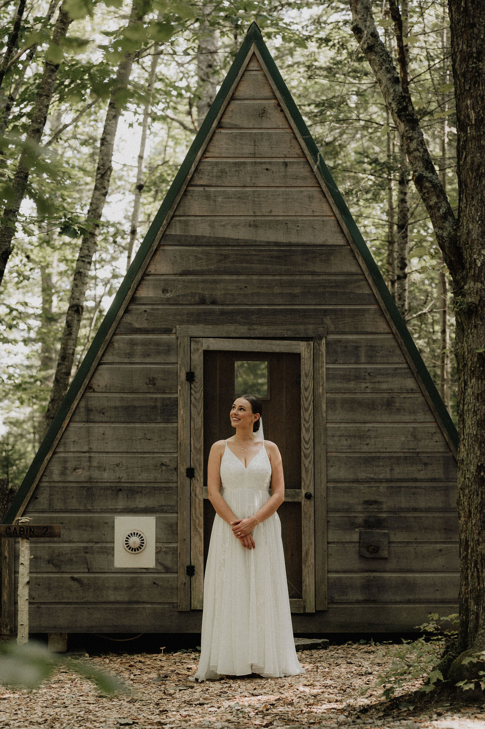 New England bridal standing outdoors in the woods with a smile