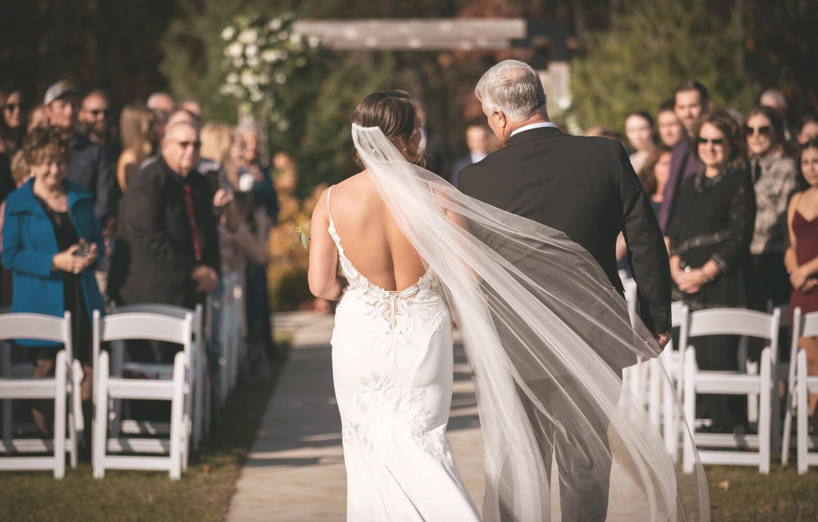 bride and her father start down the aisle with the crowd atching