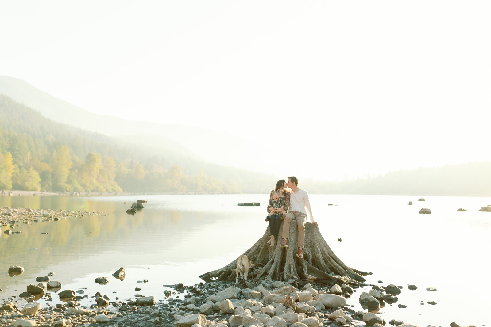 Landcape photo of family sitting on stump at golden hour at Rattlesnake Lake in North Bend, Washington.