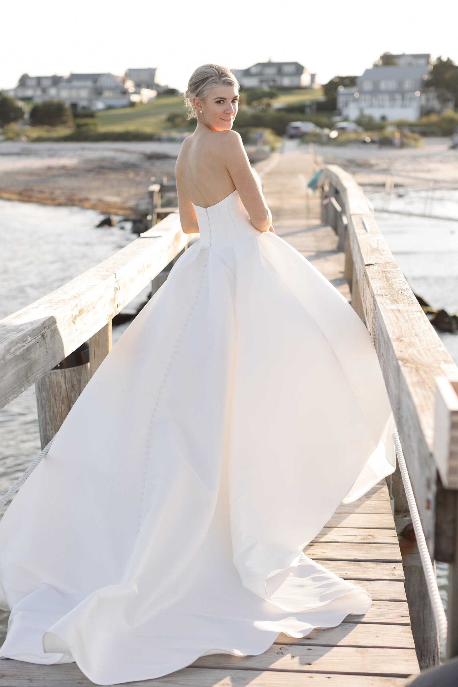 Bride looks over her shoulder while standing on boardwalk during sunset.