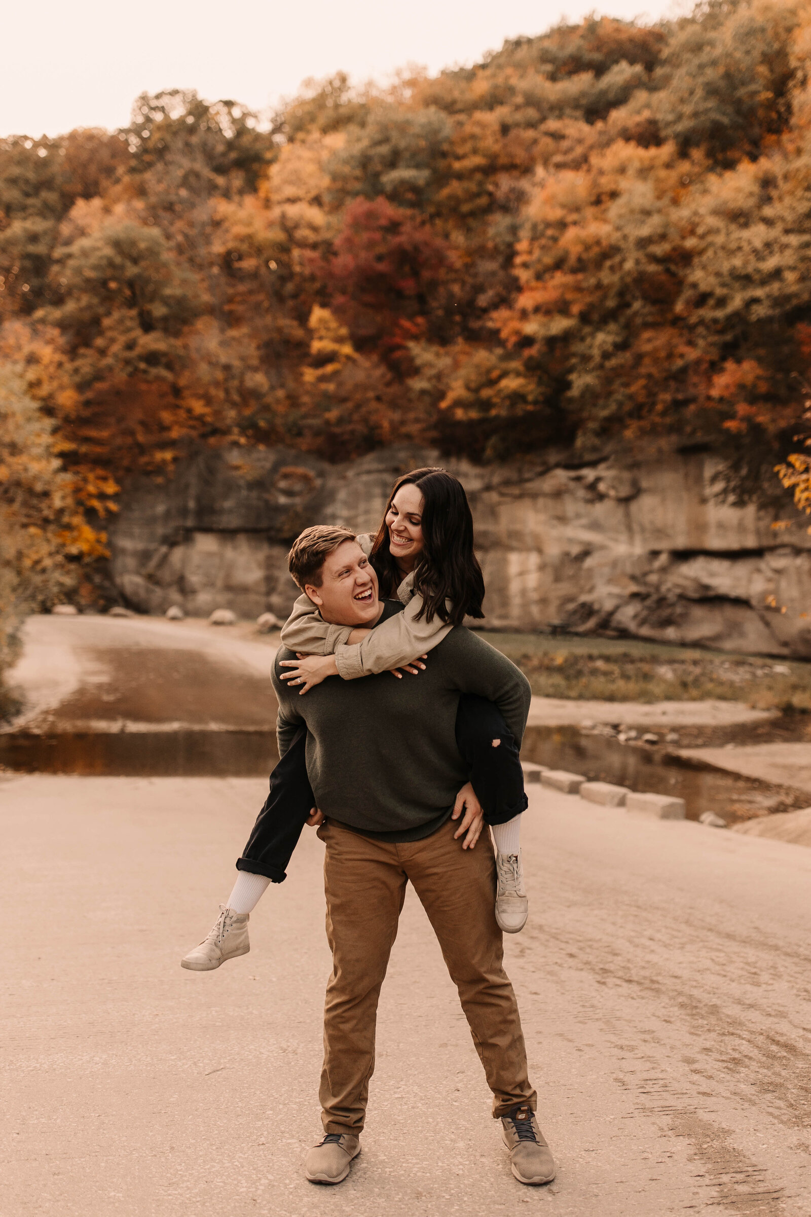 couple piggy back ride in front of the fall colors