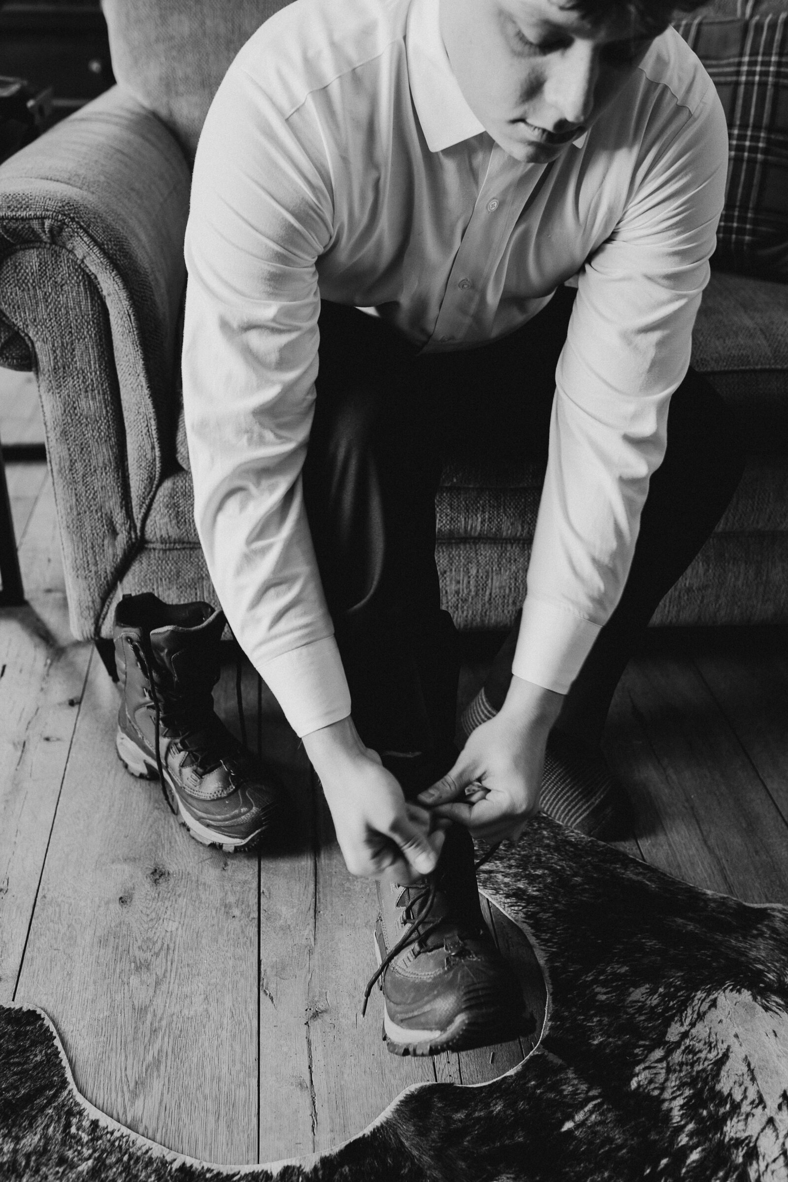 Groom ties shoes prior to wedding