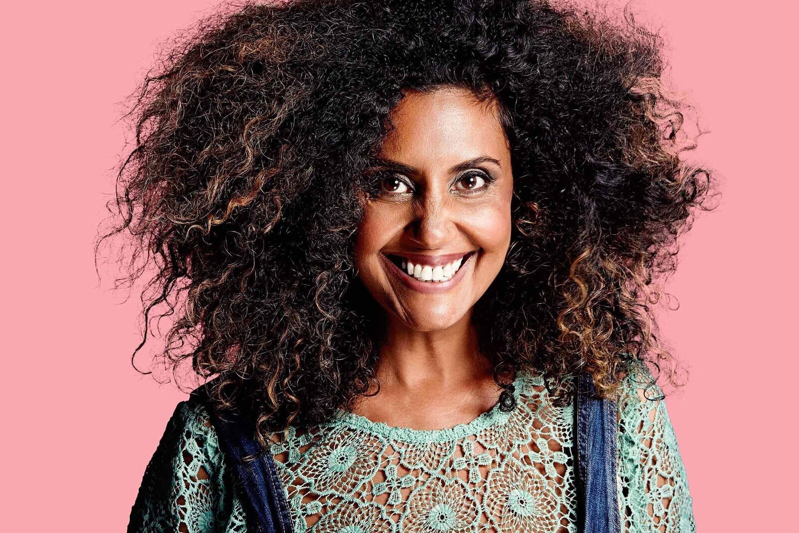 Hero image of woman with afro hair, big smile against pink background.