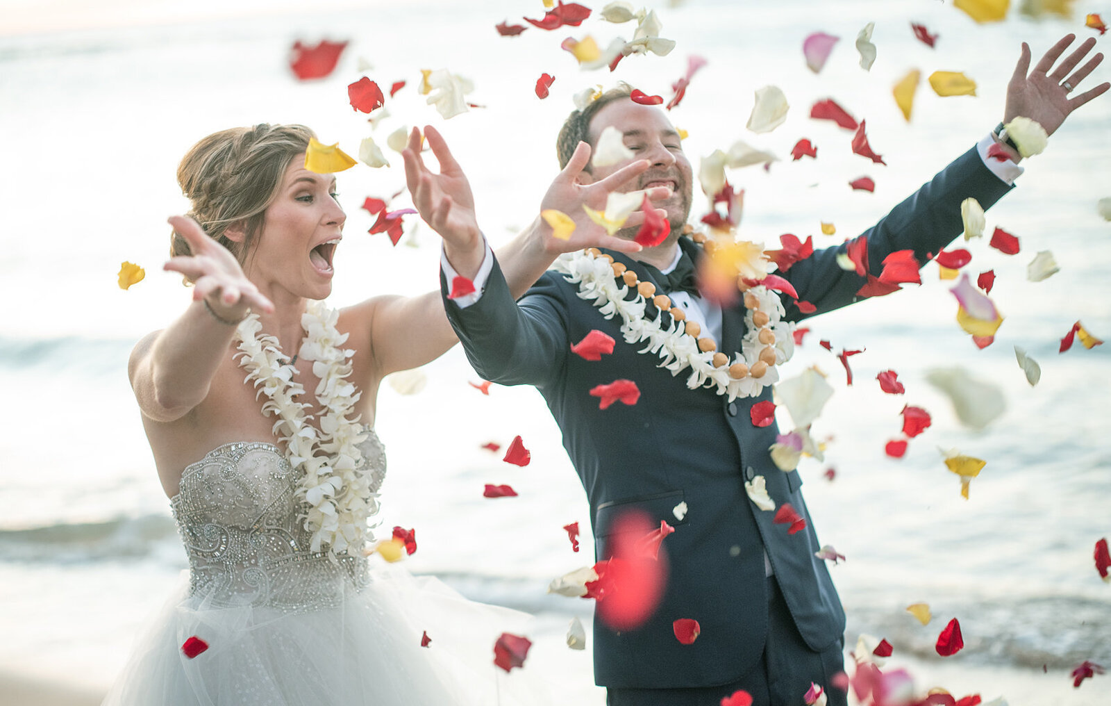 Congratulations, flowers being thrown into the air by a very happy married couple on the beach in Waikiki