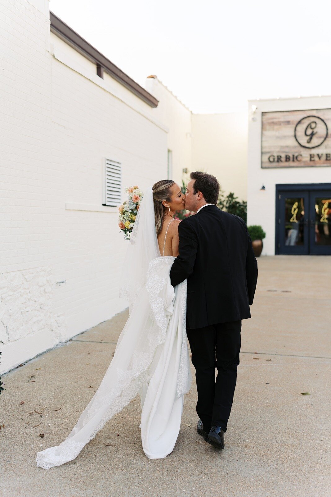 bride and groom sharing a passionate kiss outside the grbic events wedding venue in st. louis