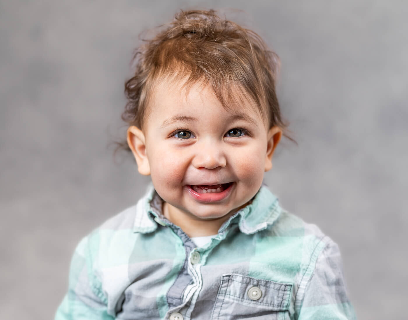 A child smiles in a button up shirt.