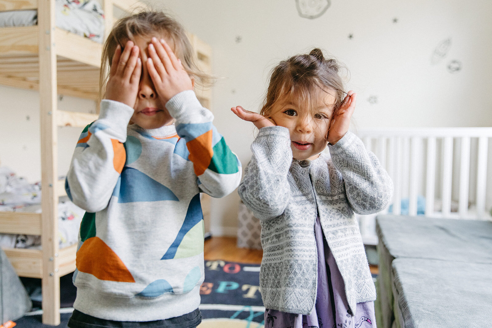 photo of two young kids playing peekaboo with the camera