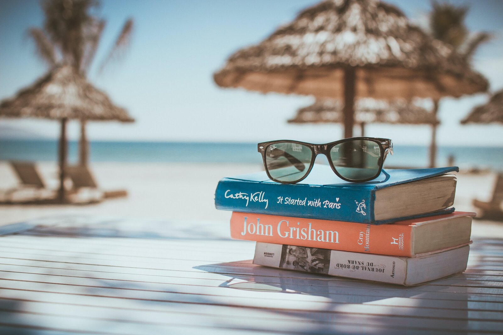 several books stacked on a table overlooking the ocean