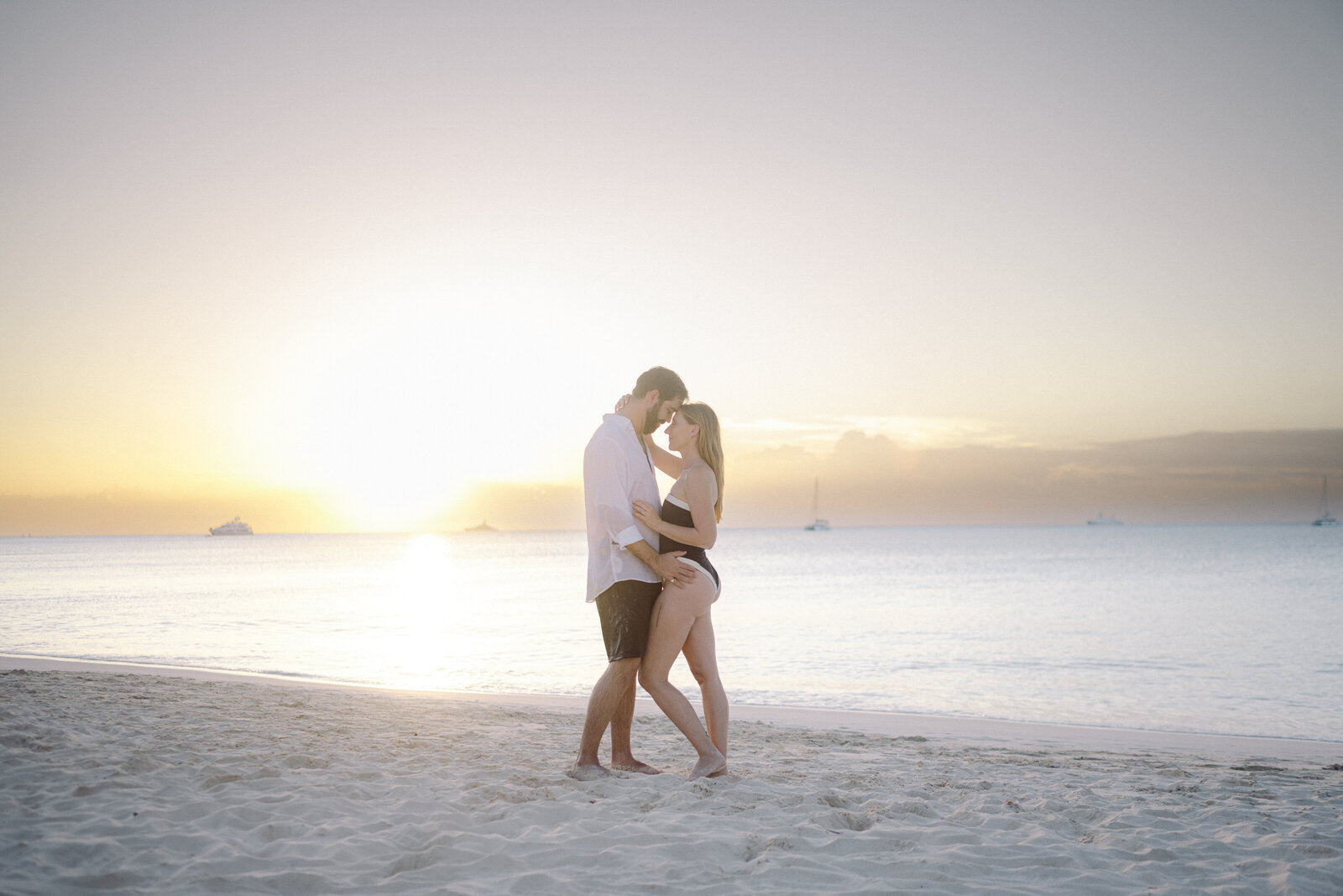 couple in beachwear embracing at sunset in the Bahamas on a beach