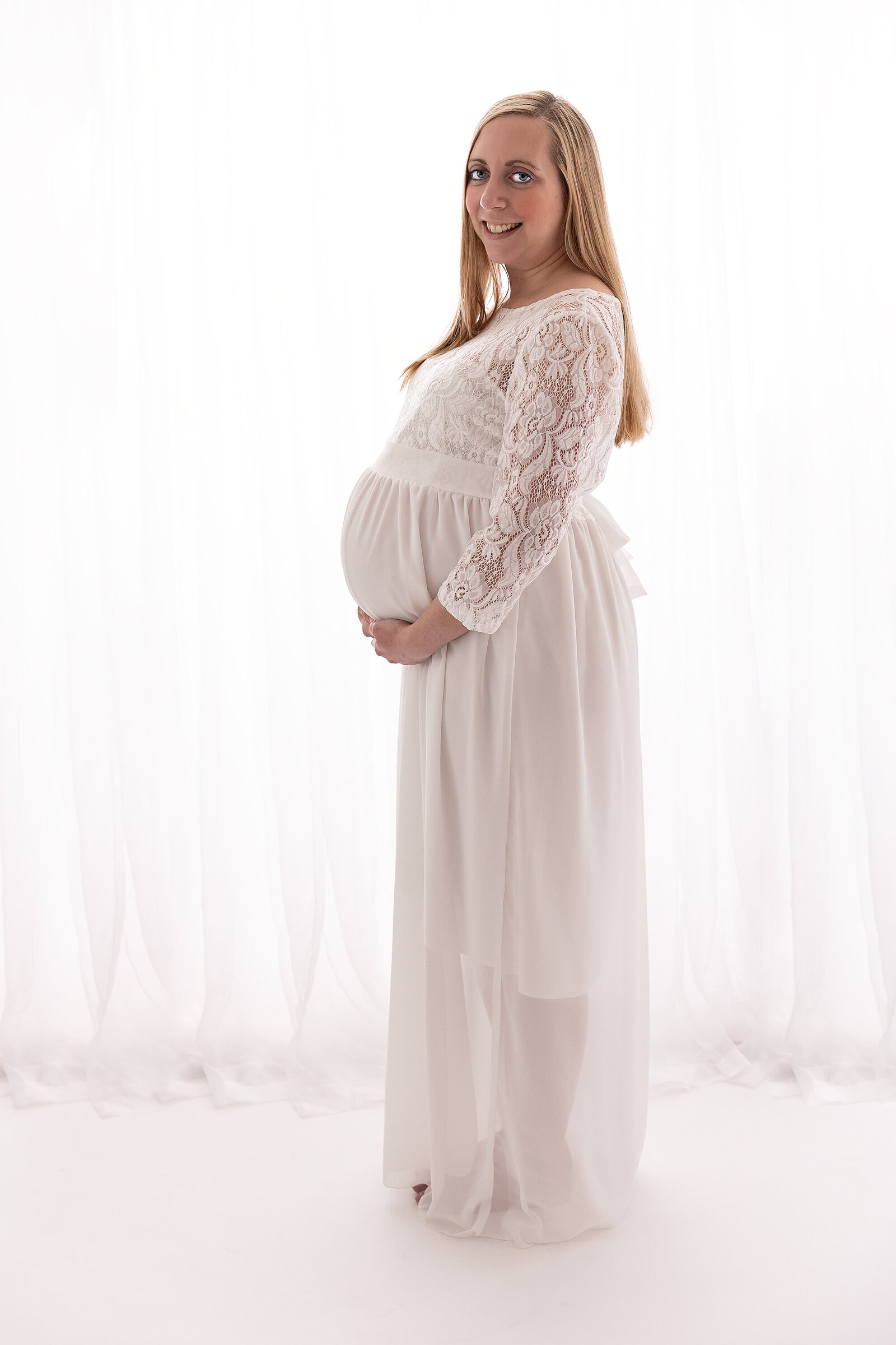 backlit studio portrait of pregnant woman looking at camera by PHILADELPHIA MATERNITY PHOTOGRAPHER
