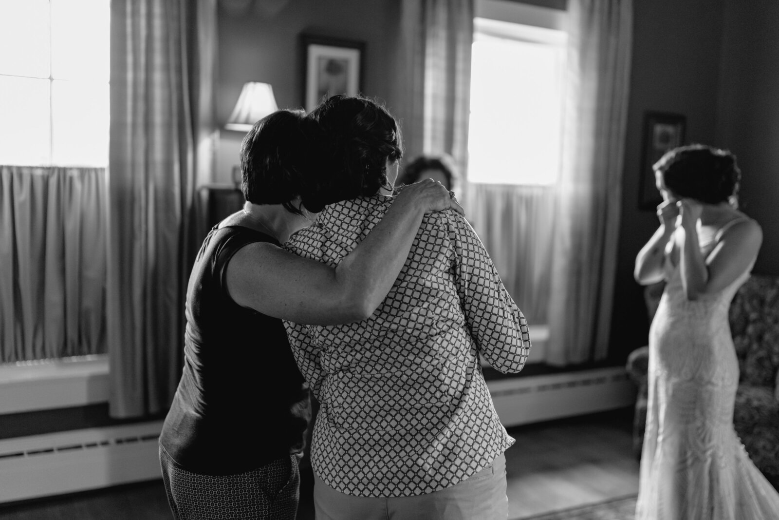 Two women look on as a bride puts on her earrings