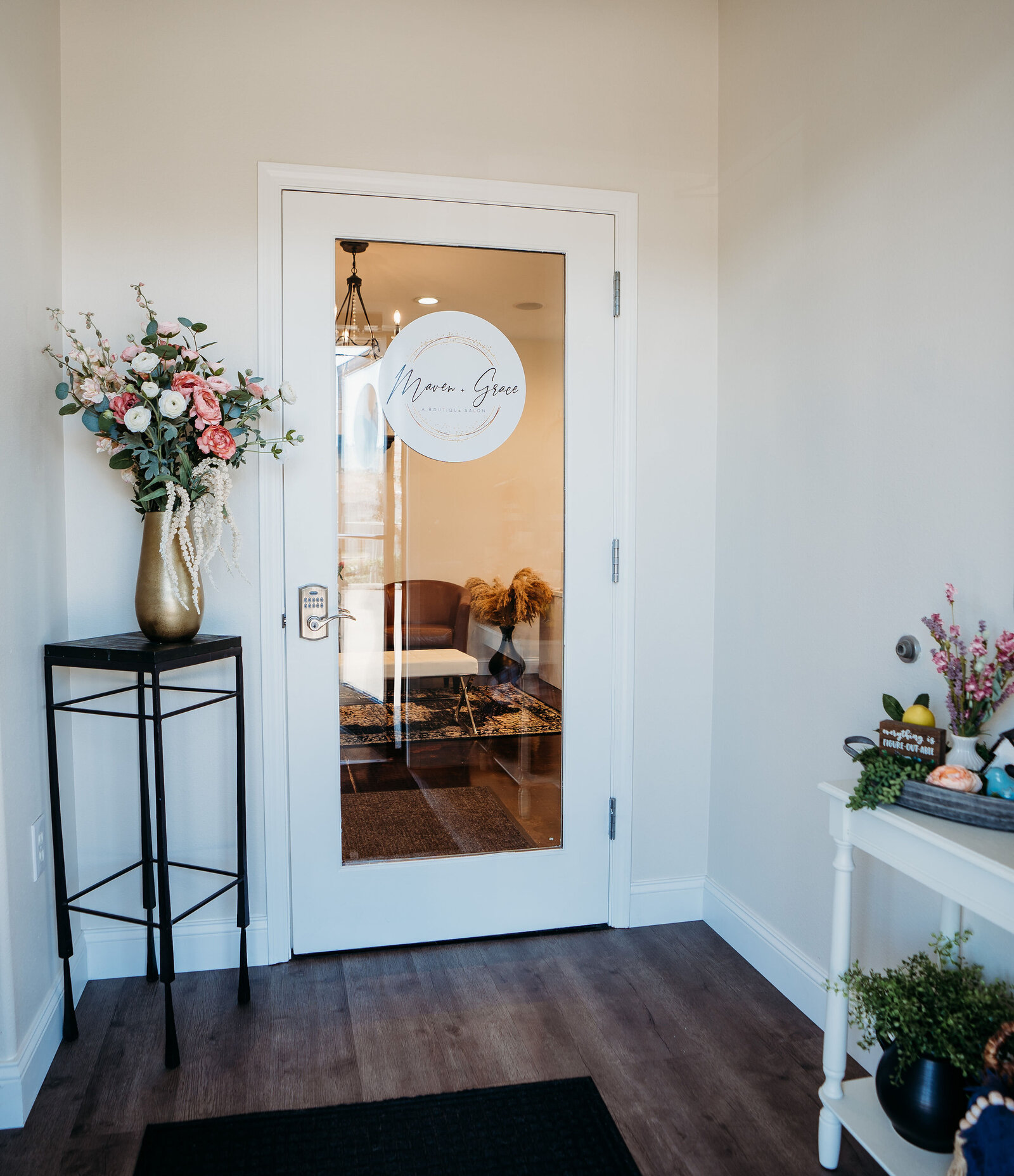 Entryway at Maven + Grace Salon in McMinnville, Oregon, with branded glass door and welcoming floral display