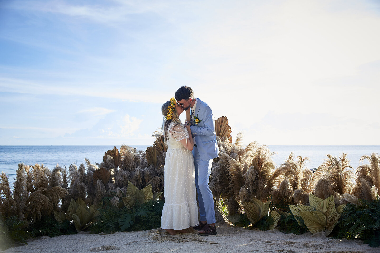 Bride and Groom kissing grounded wedding arch pampas
