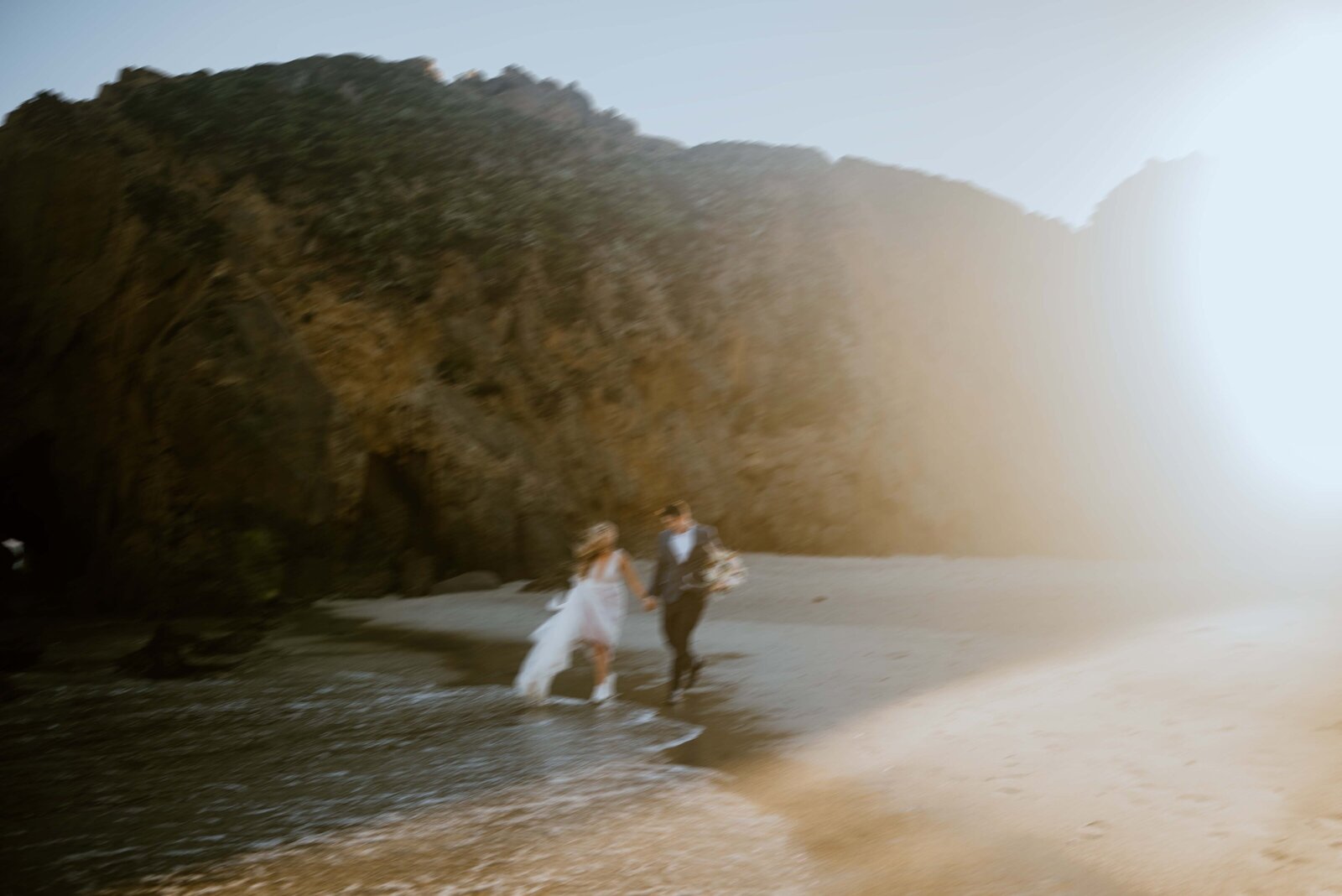 A Bride and Groom run along Pfeiffer Beach in Big Sur, California during their elopement.