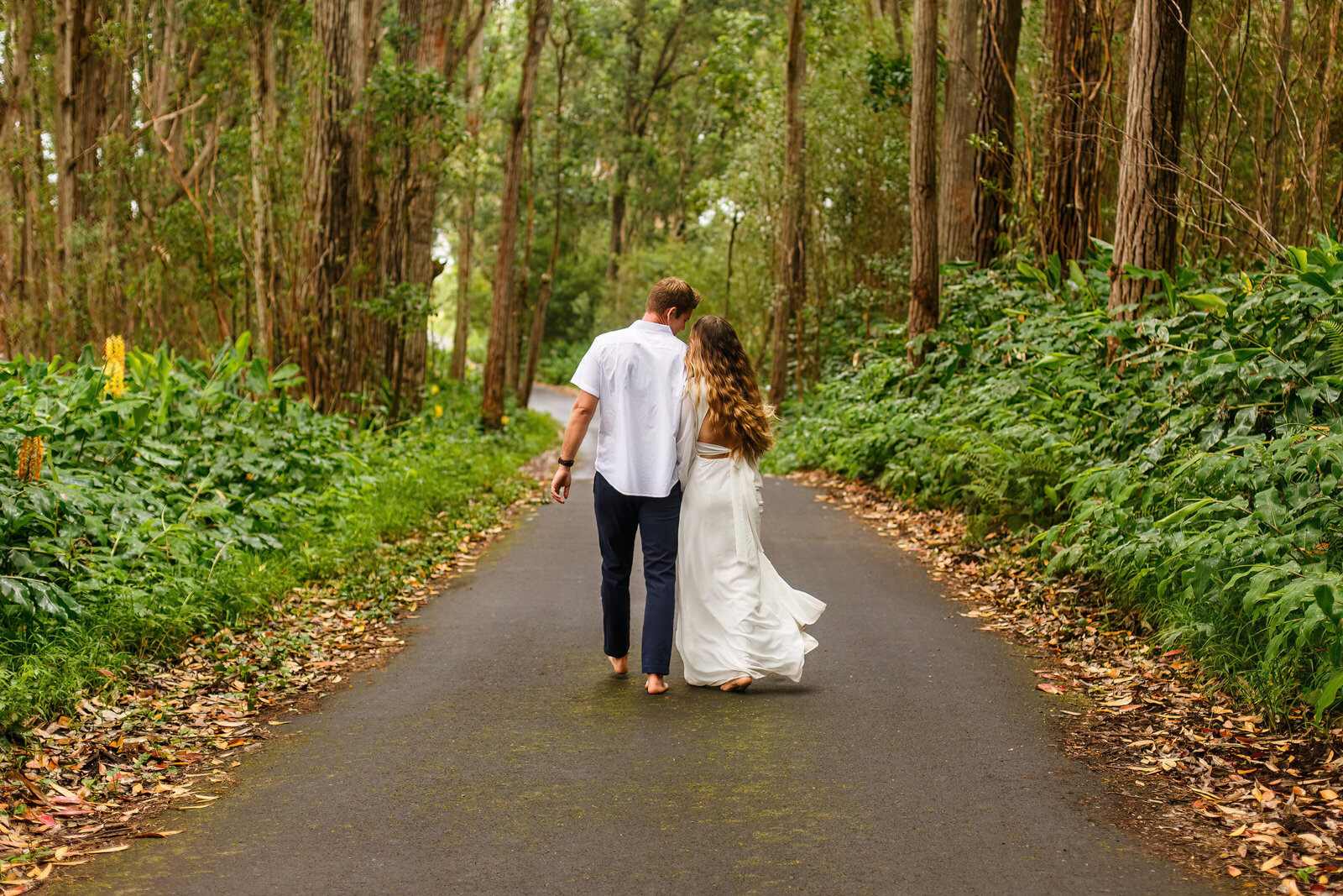 A casual eloping couple walking on a jungle road in Hawaii