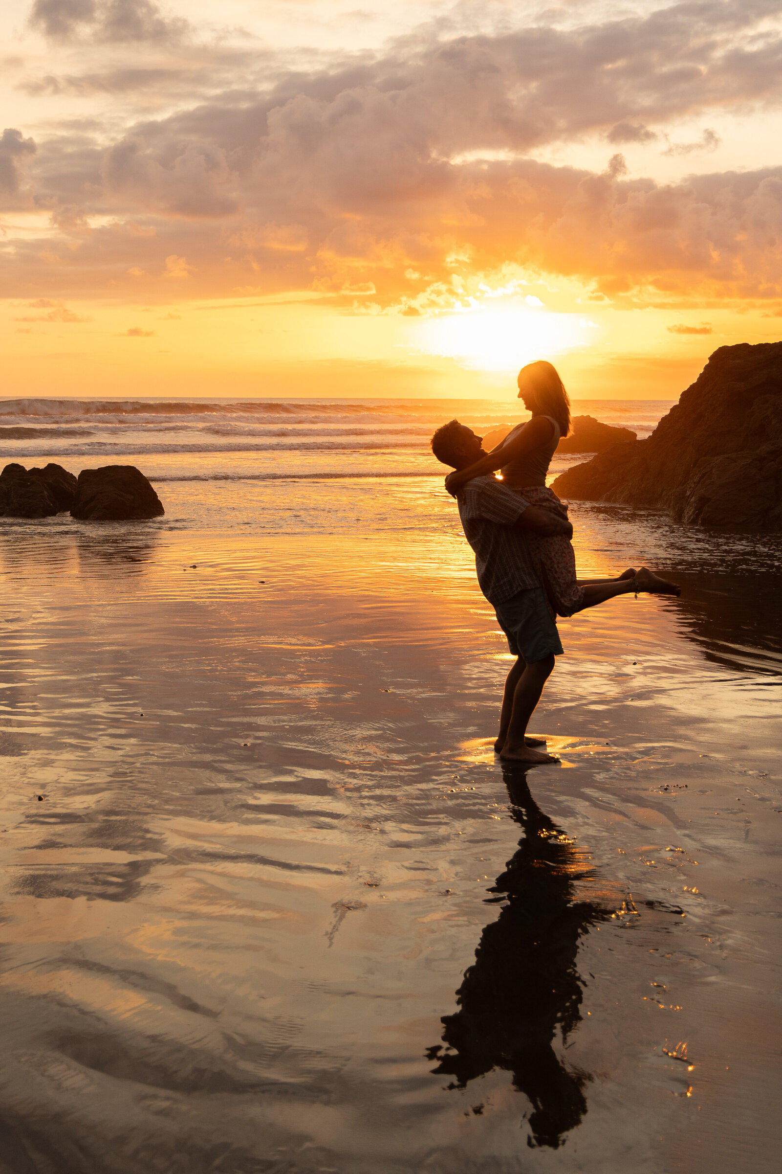 man picking up woman on the beach couple silhouette 