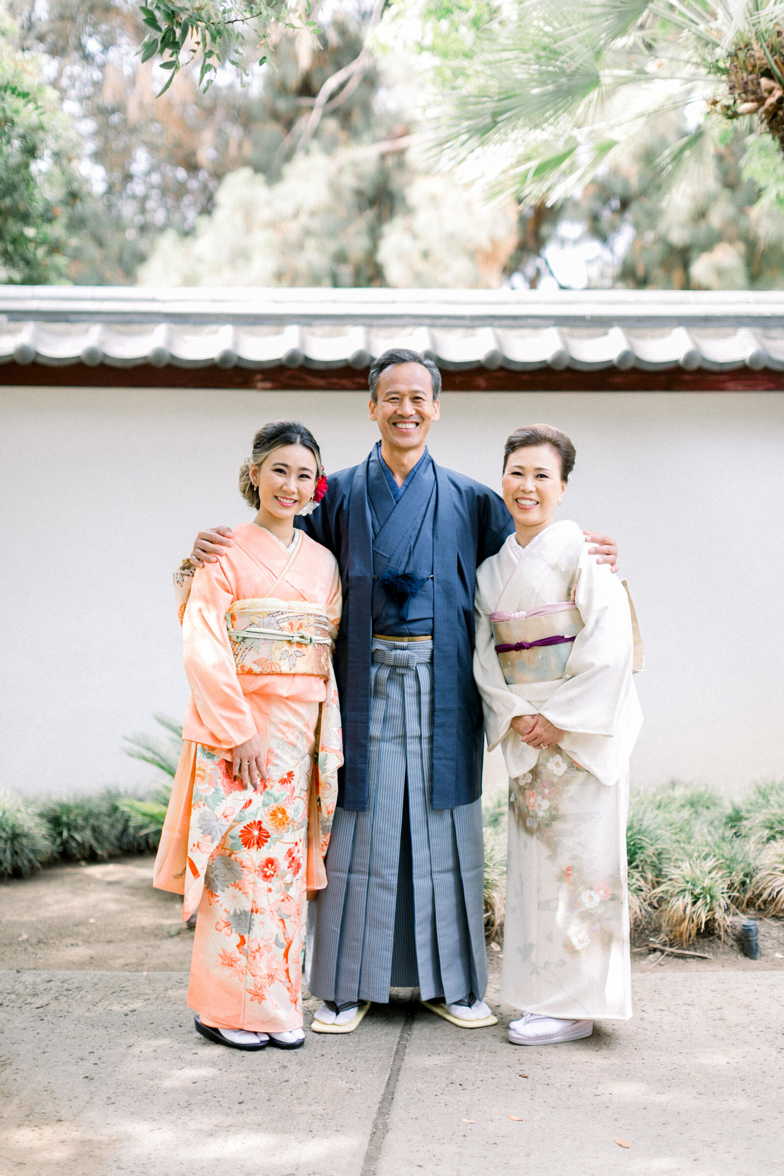 Elegant family portrait at Brand Park the Shoseian Whispering Pine Japanese Tea House Glendale for a Seijinshiki (coming-of-age) celebration, daughter in soft peach furisode with parents in traditional kimono, kimono rental Los Angeles | ロサンゼルス・ブランドパークでの成人式、淡いオレンジ振袖の娘と和装の両親による上品な家族写真、着物レンタル