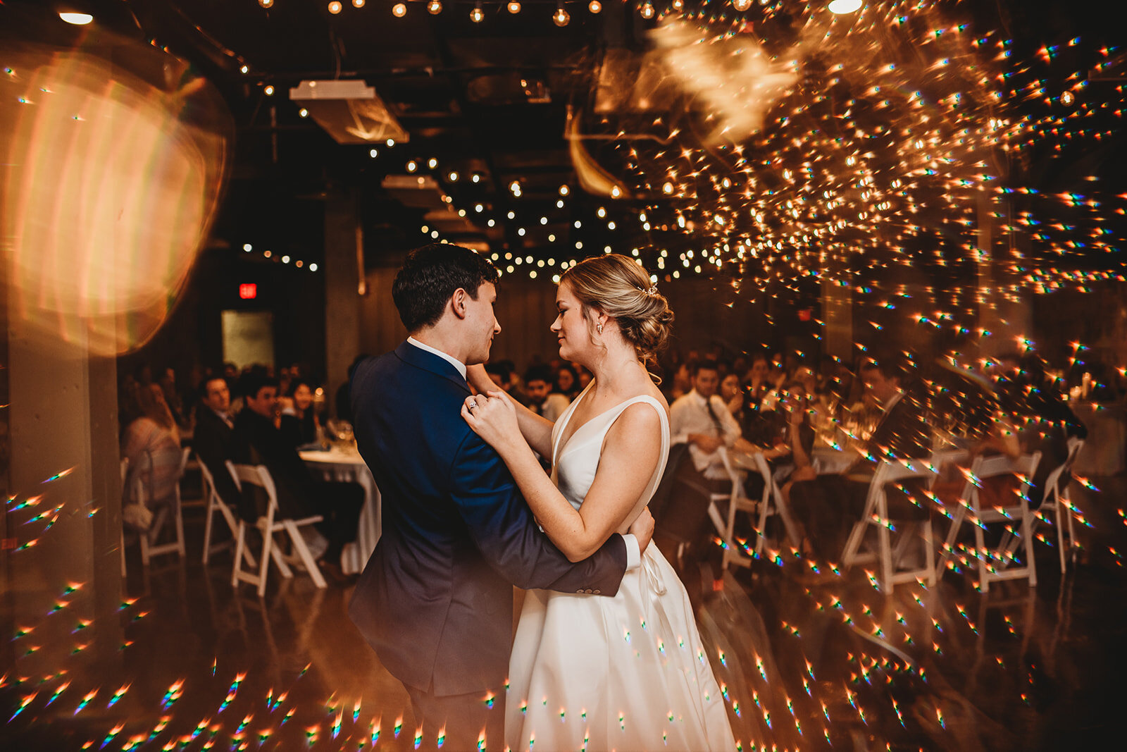 Bride and groom dancing during their wedding reception with twinkle lights over had captured by Baltimore photographers