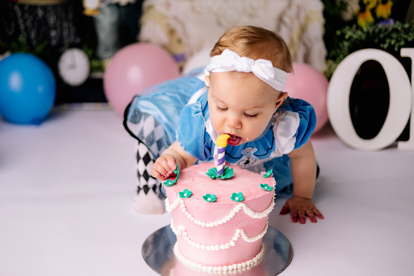 Sweet baby girl leans in to take her first taste of birthday cake