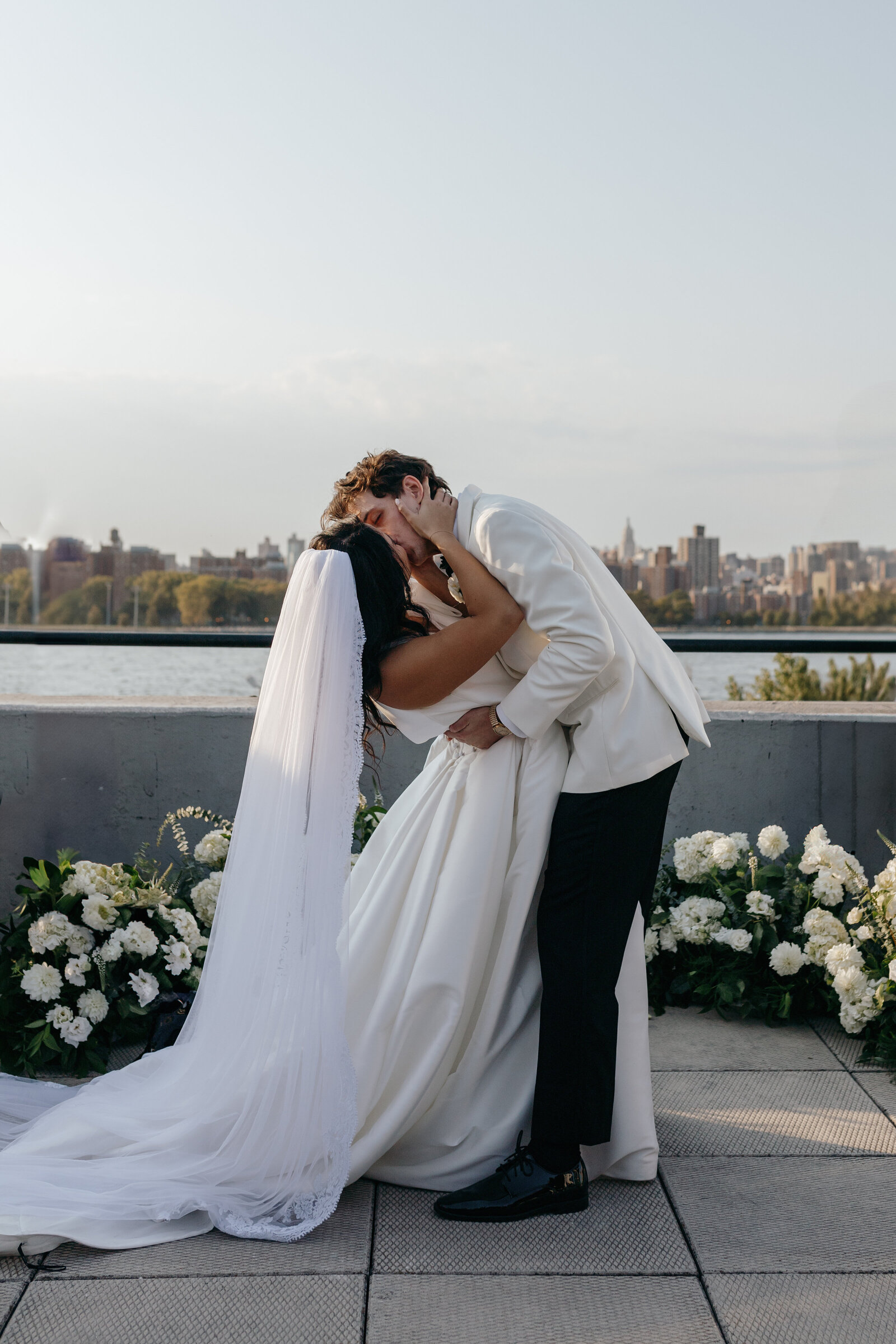 Groom dipping bride in romantic kiss lakeside at venue in Long Island, NY | Emma LeeAnn Photography