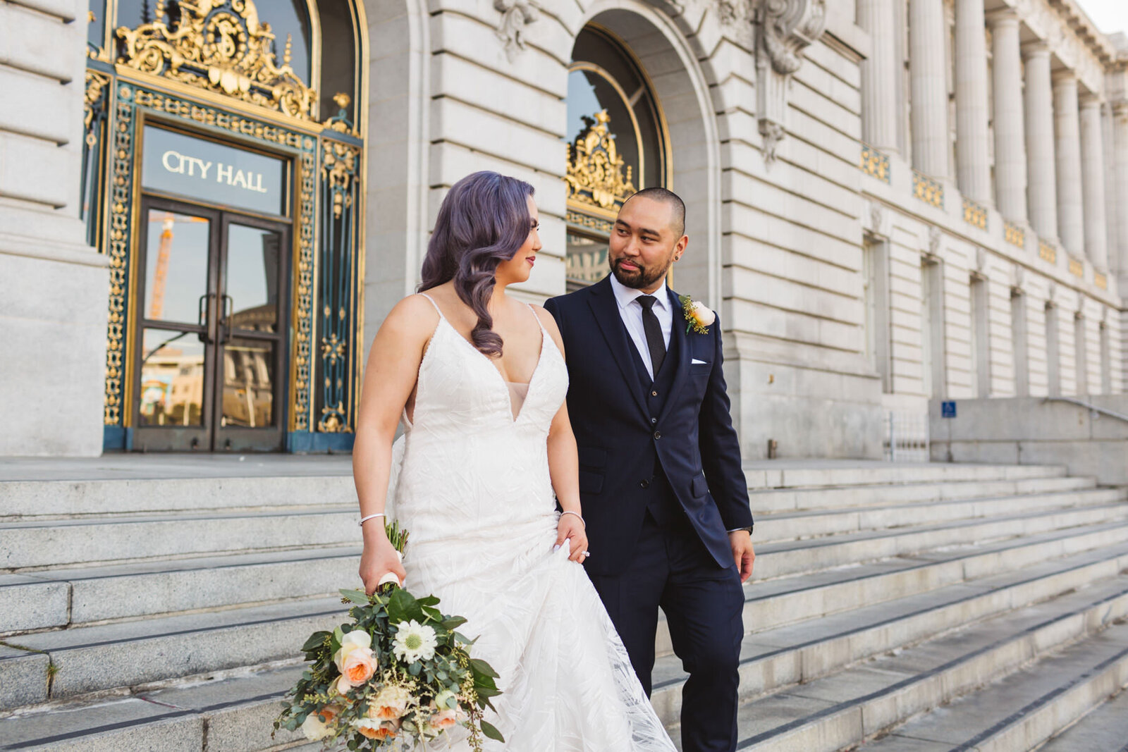 bride and groom walking out of SF City Hall
