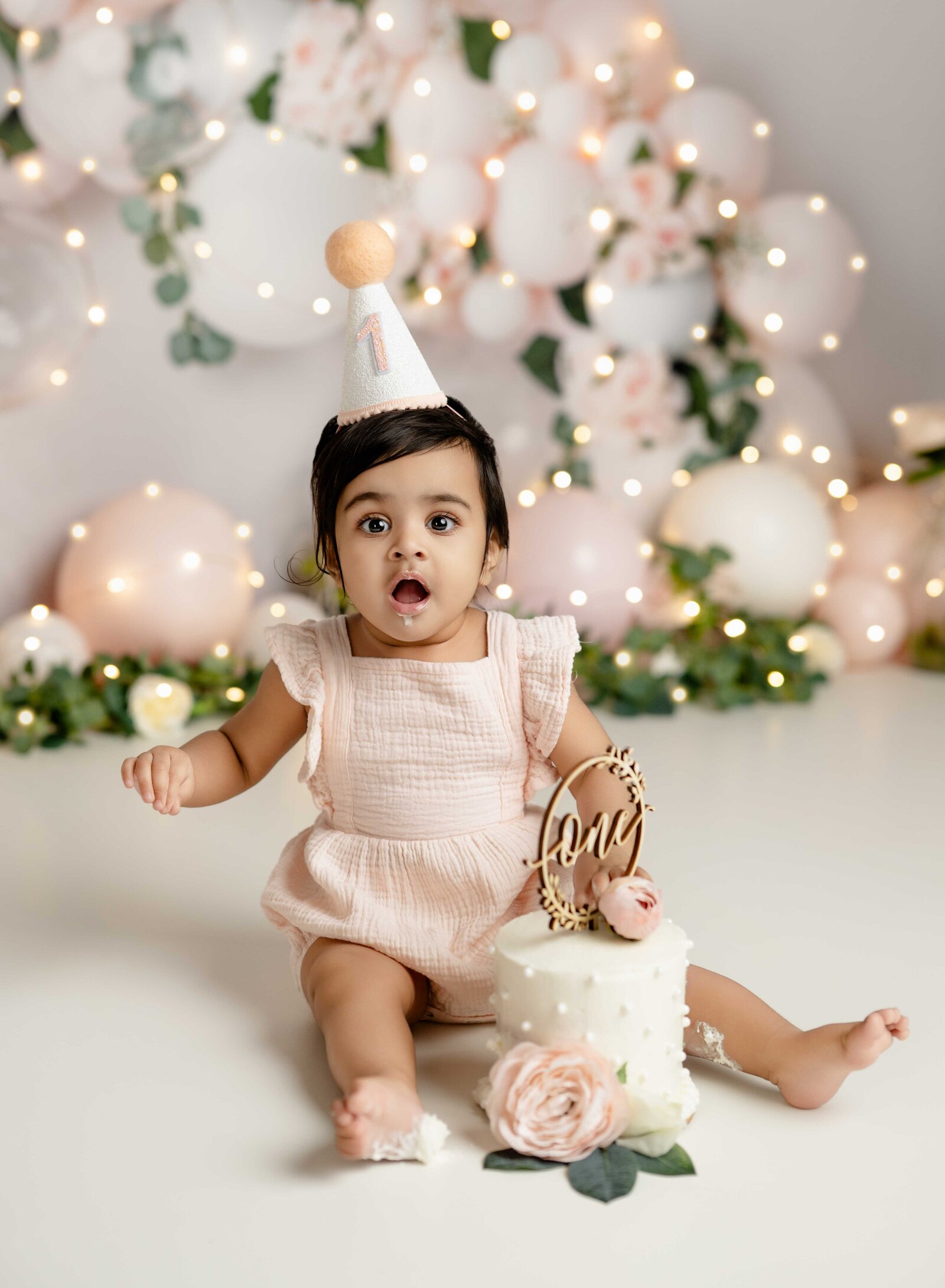 Baby girl eating cake and having a surprise face. Cake Smash photo taken by Jenni Nikki in Atlanta, GA