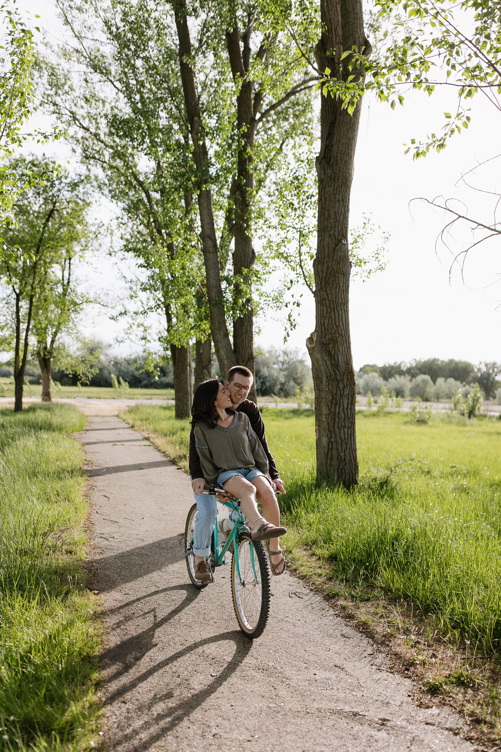 Couple laughing while riding bicycle during playful couples shoot
