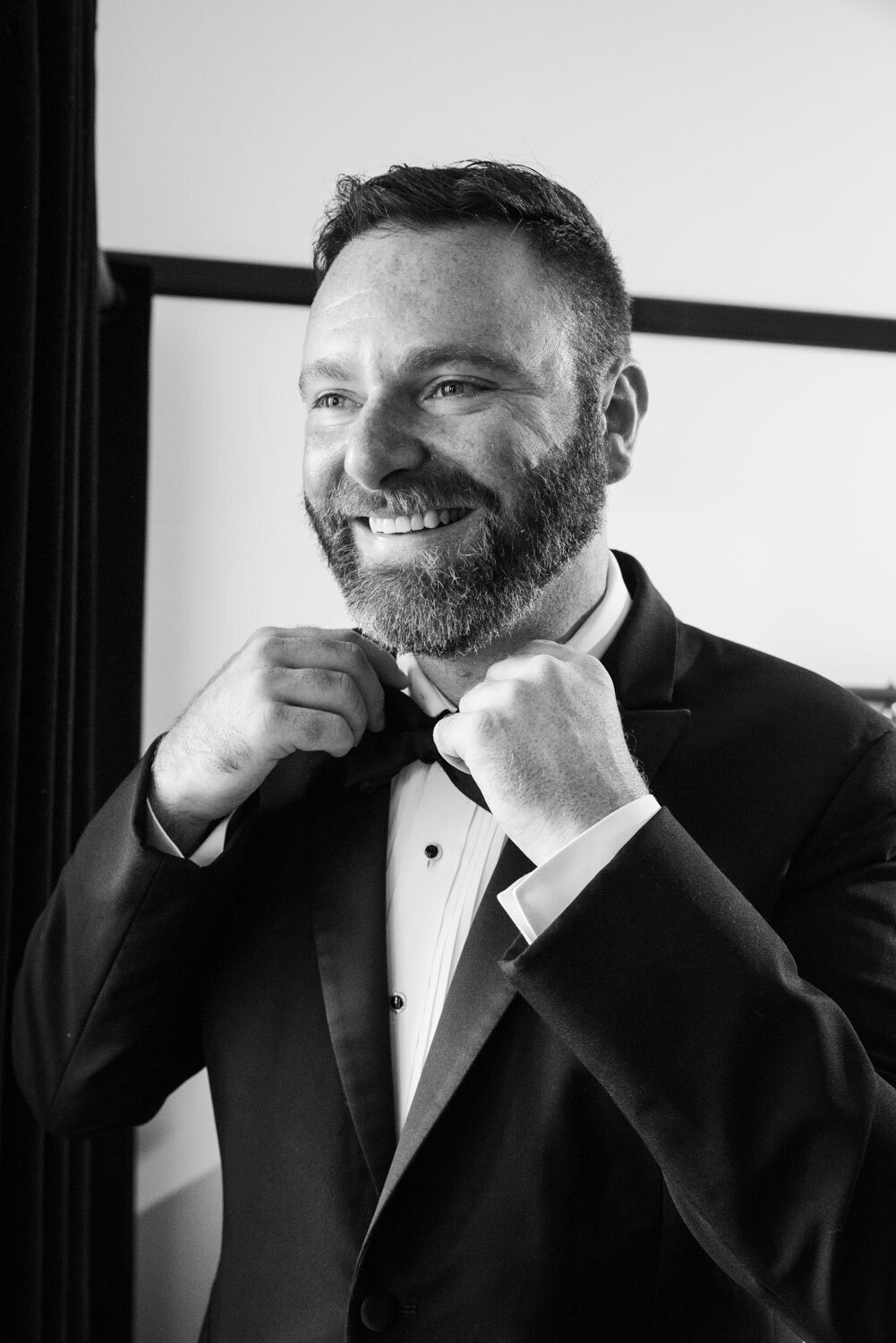 A man with a beard is wearing a tuxedo and bow tie.