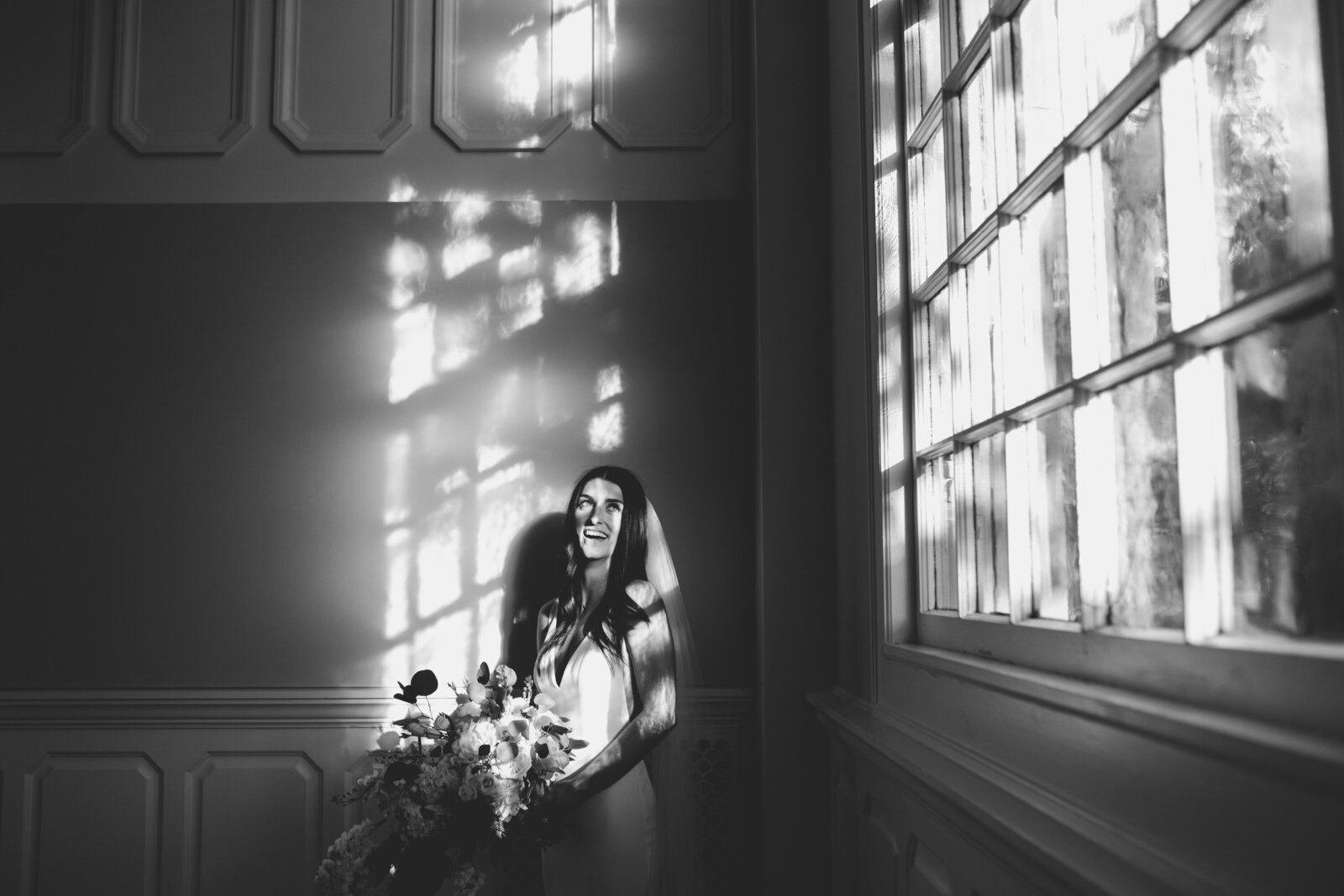 A bride smiles in front of a window.