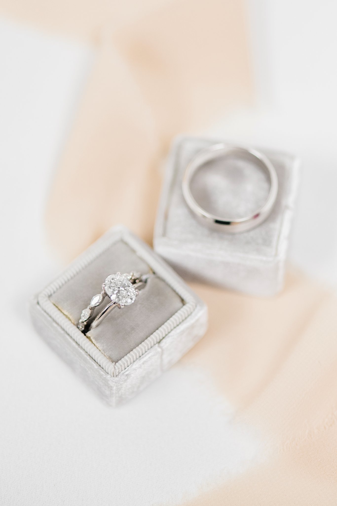 An oval-cut diamond engagement ring sits on a silver velvet ring box.