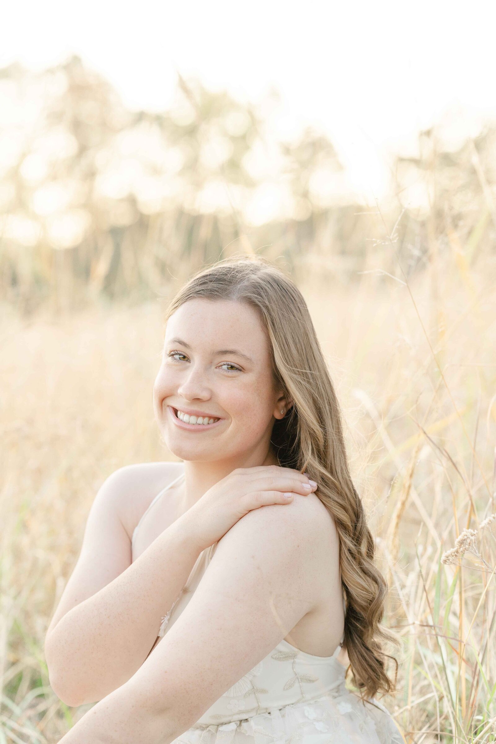 girl pose in a field during senior photo in Loudoun County, VA