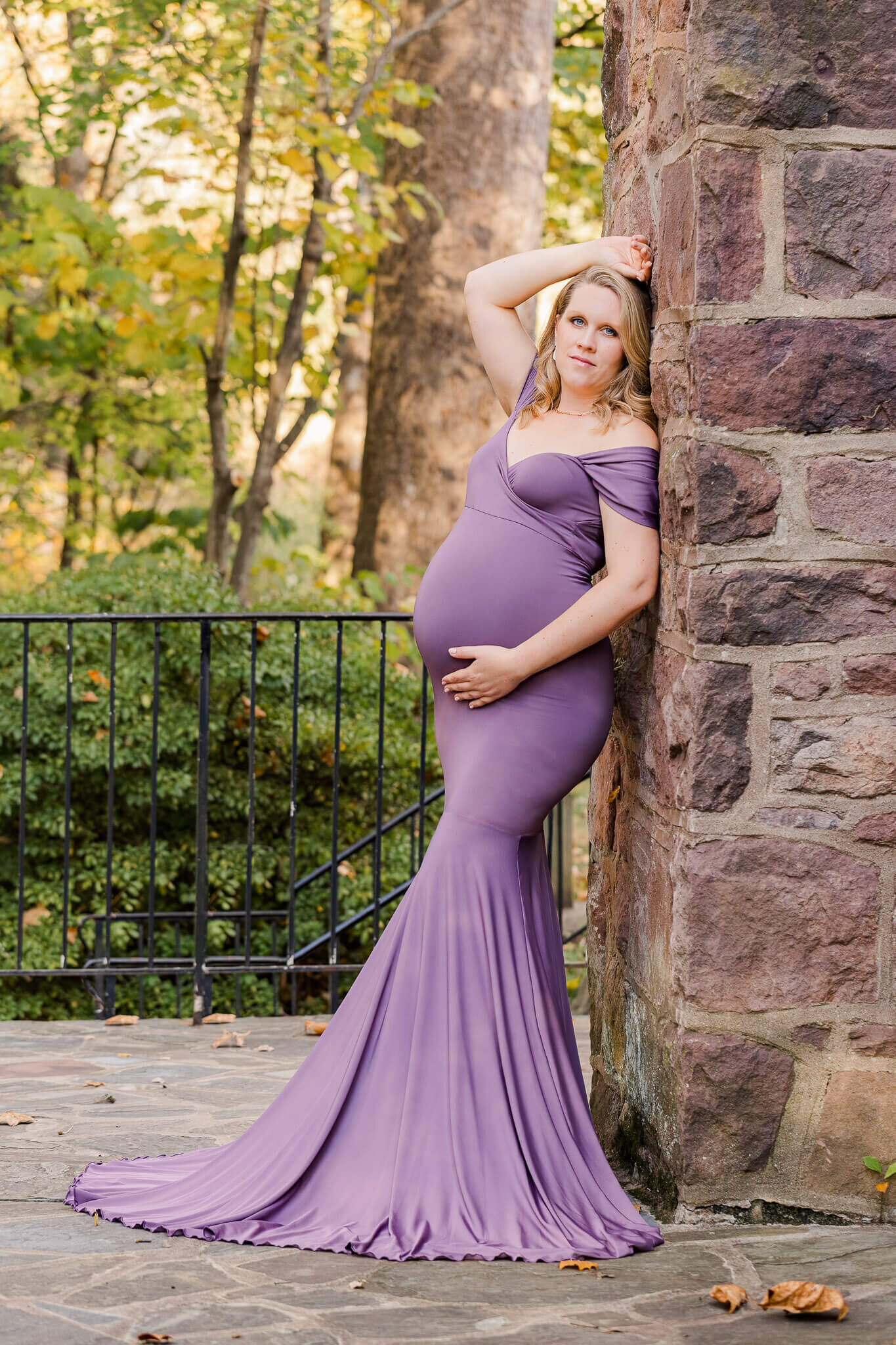 A woman posing against a brick wall for her Northern VA maternity portrait session.
