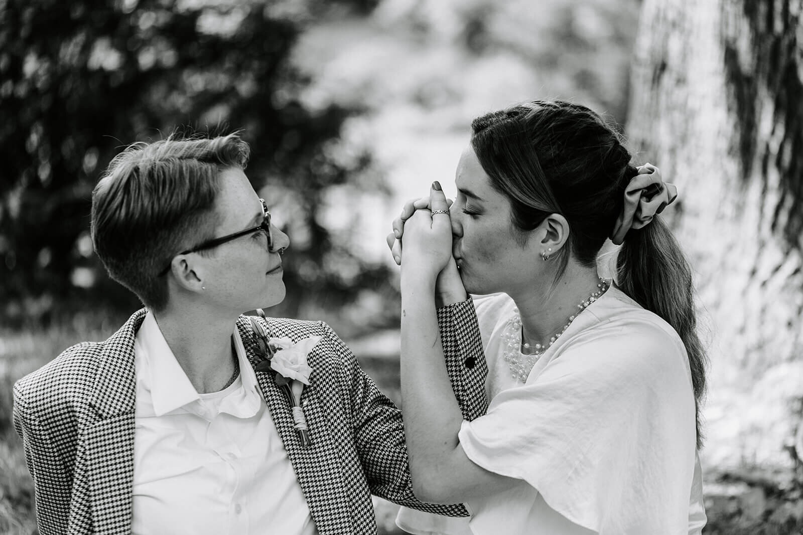 queer newlywed couple kissing hands after wedding