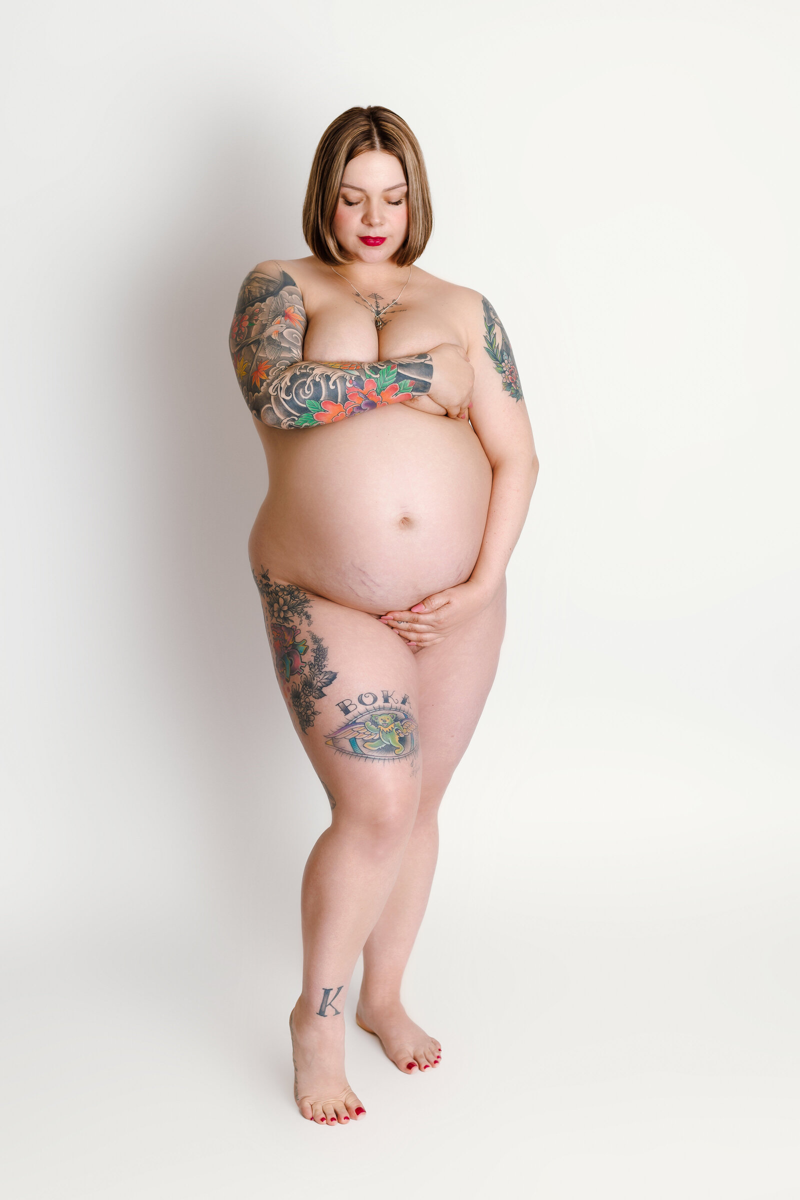 Maternity Photographer, a pregnant woman is not wearing clothing, her tattoos exposed