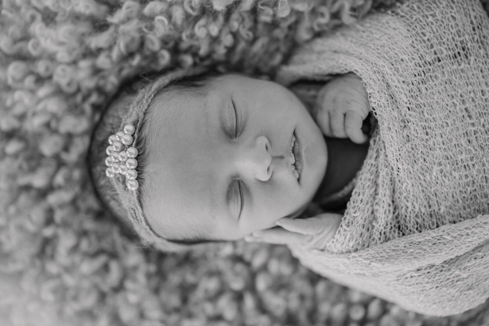 black and white portrait of newborn girl holding her face while sleeping