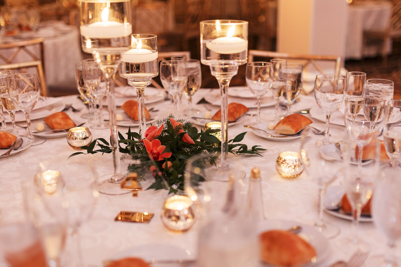 Floral table centerpieces surrounded by floating candles,