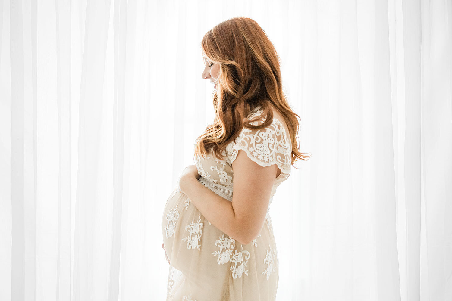 pregnant woman front of white curtains