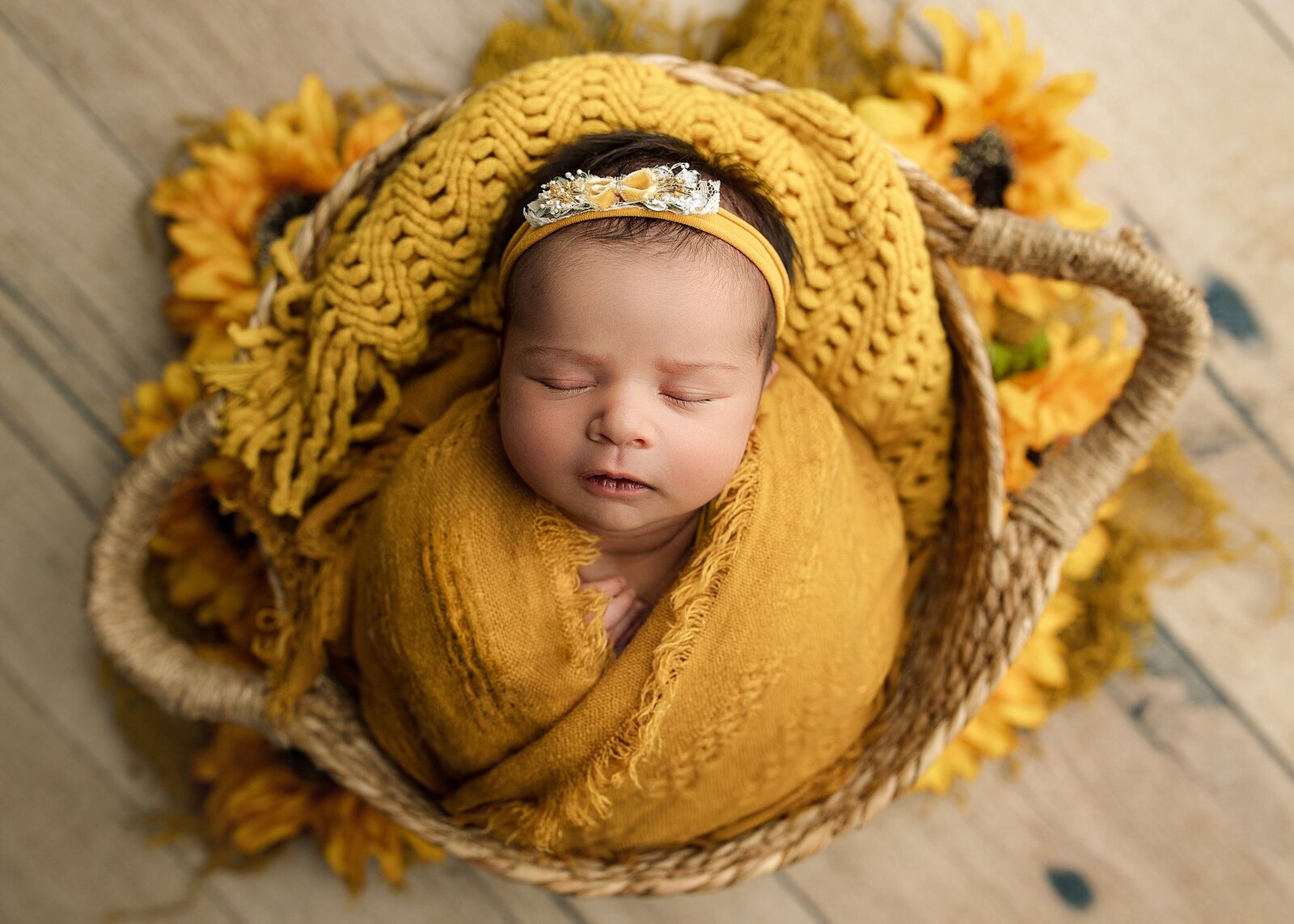 baby girl wrapped in yellow in a basket prop.