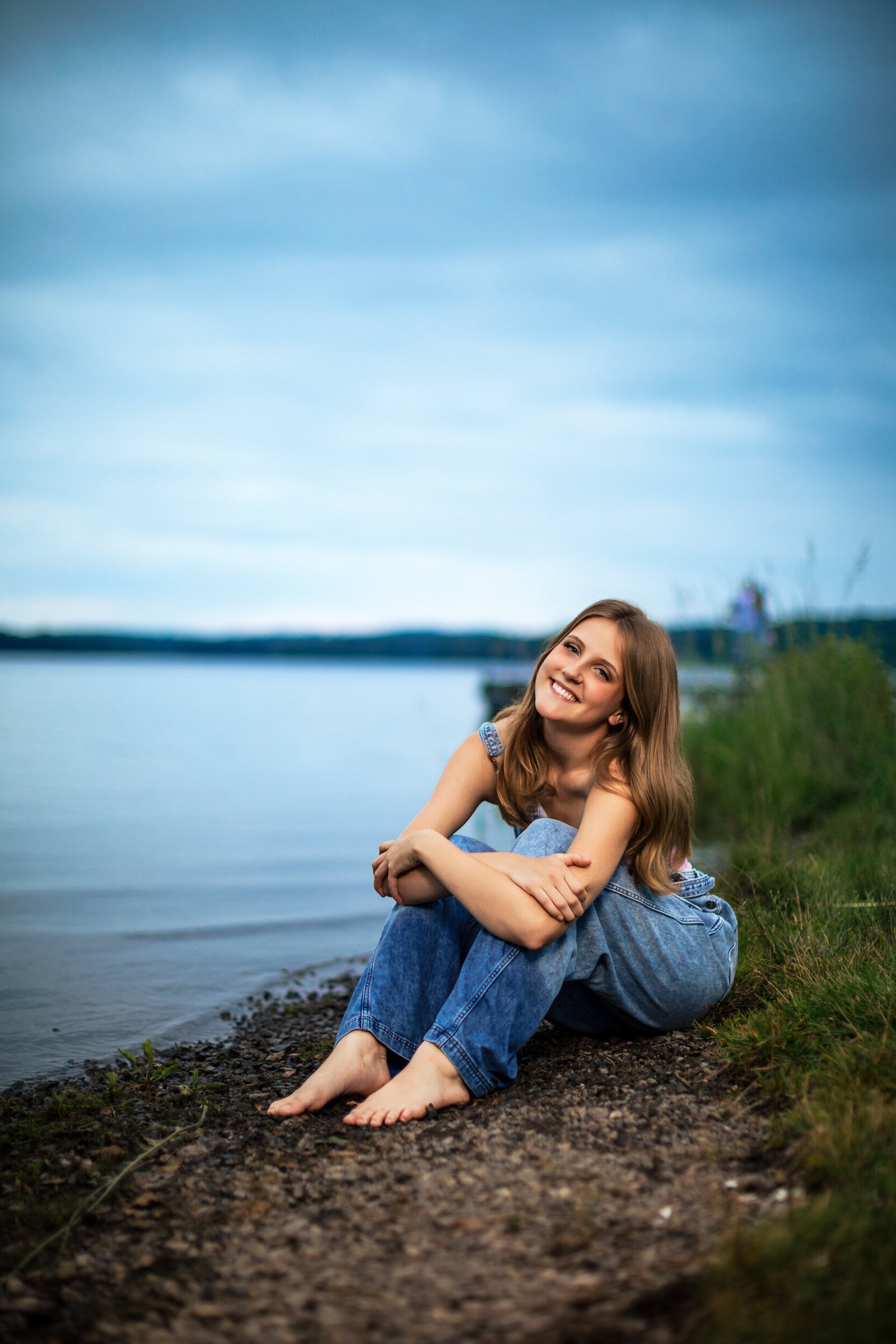 The girl sits next to the water and the dock at the state park north of Pittsburgh