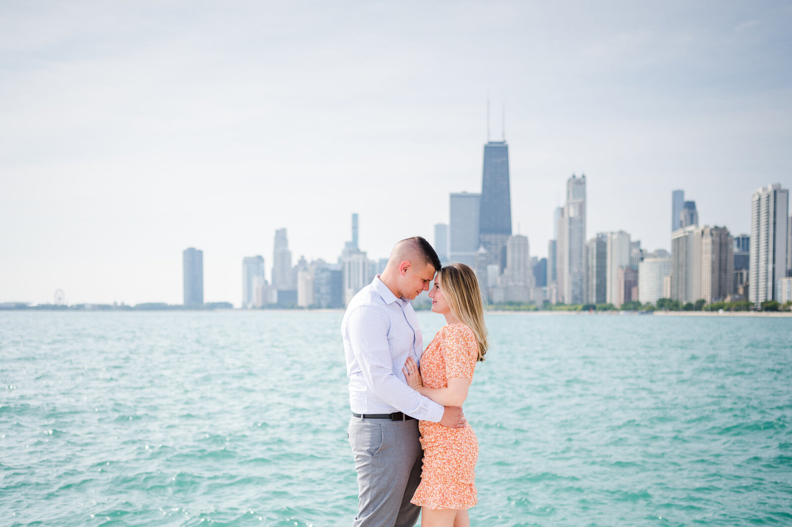 Newely engaged couple sharing a moment on North ave beach overlooking the Chicago skyline.