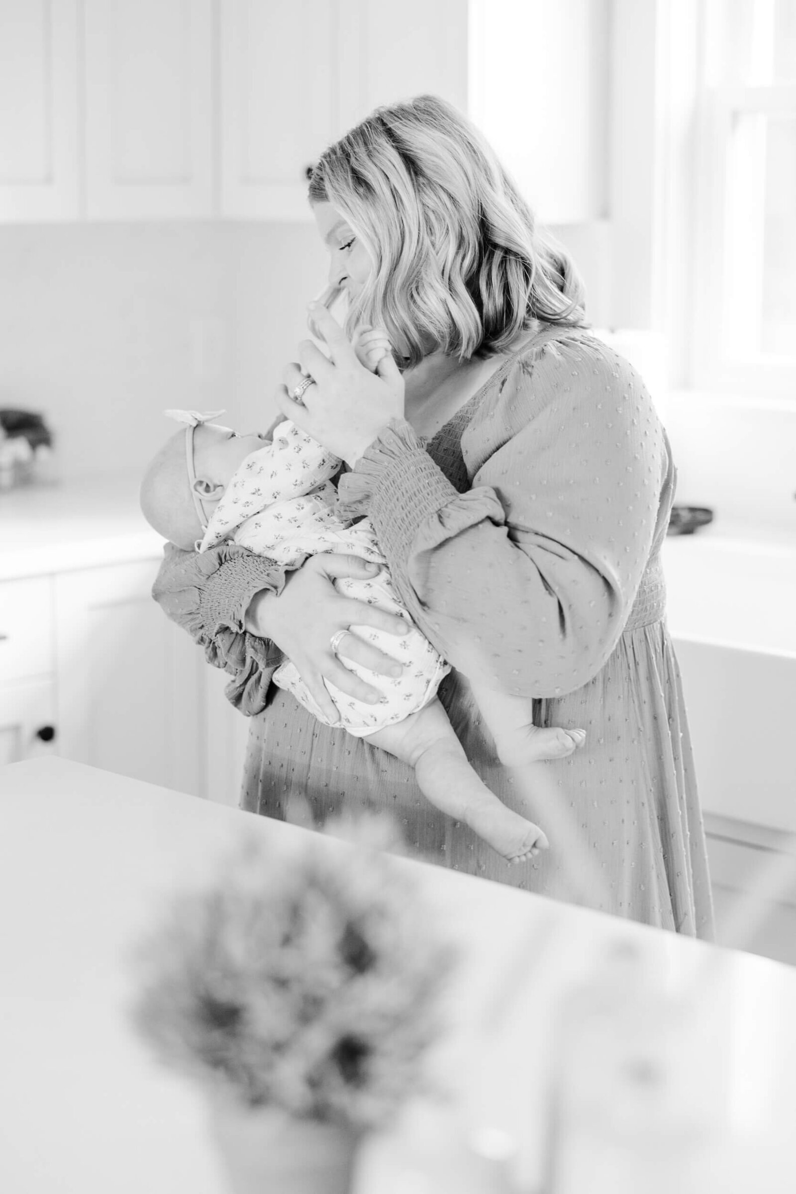 Black and white, mom feeds baby a bottle in the kitchen