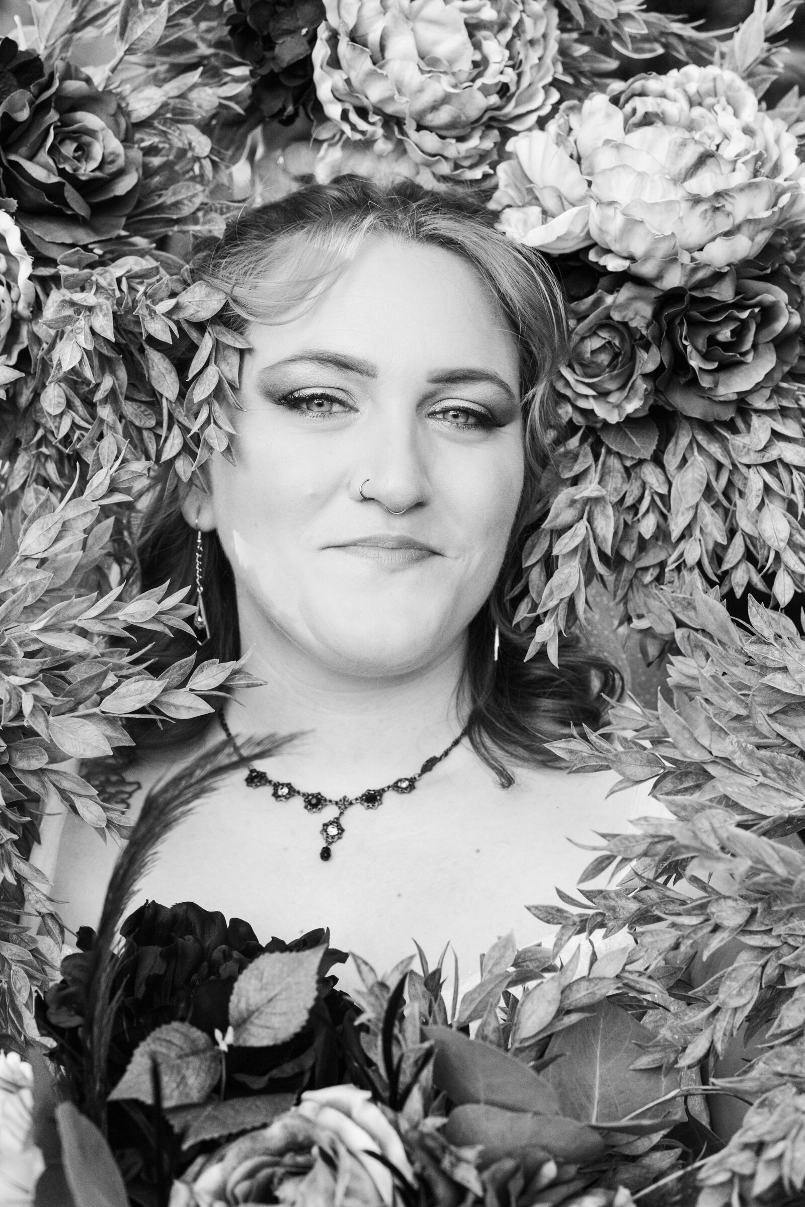 Tattooed groom with colorful wedding flowers in a black and white photo.